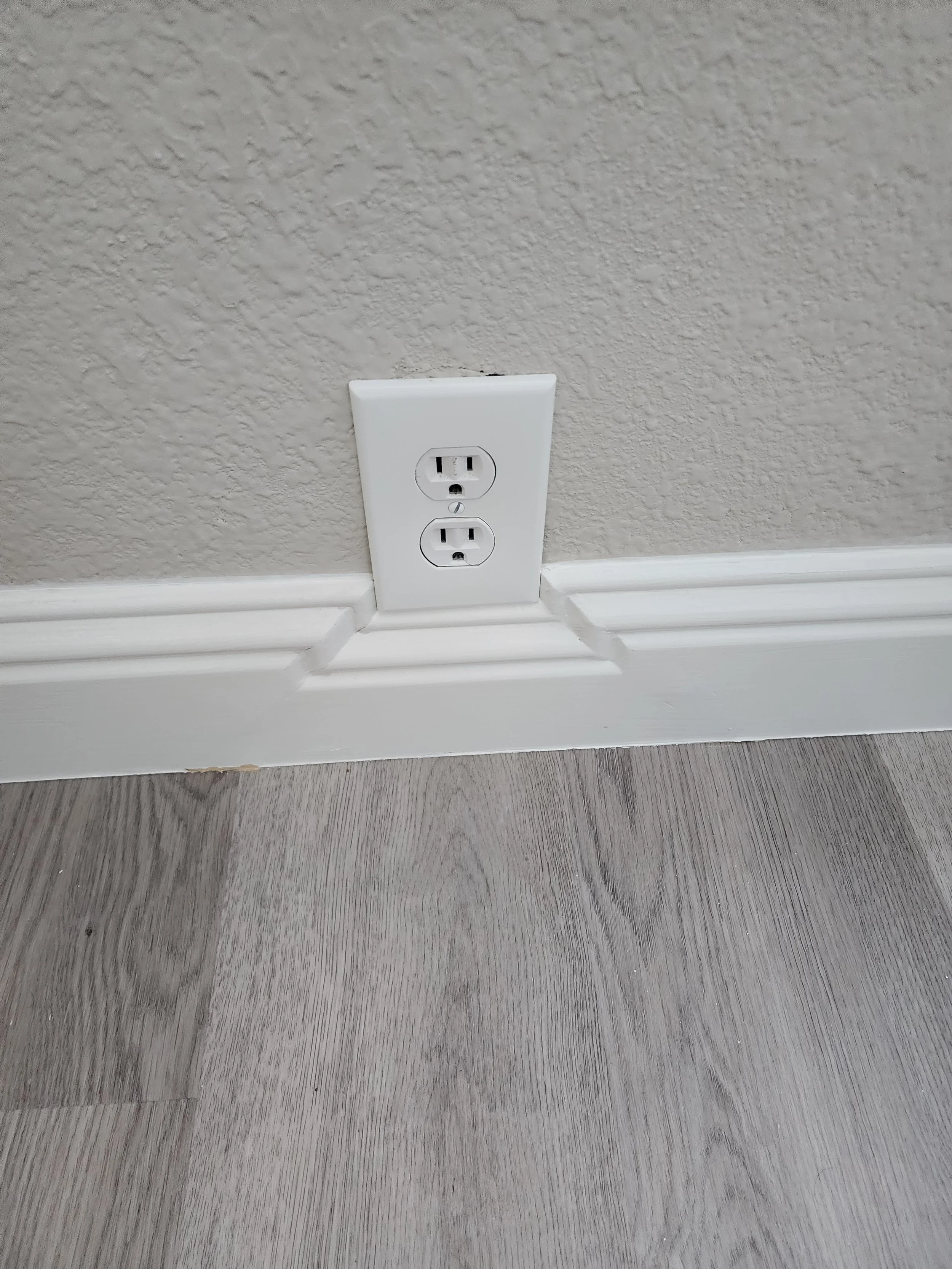 Baseboard trimmed and notched around the outlet for a clean, finished look.
