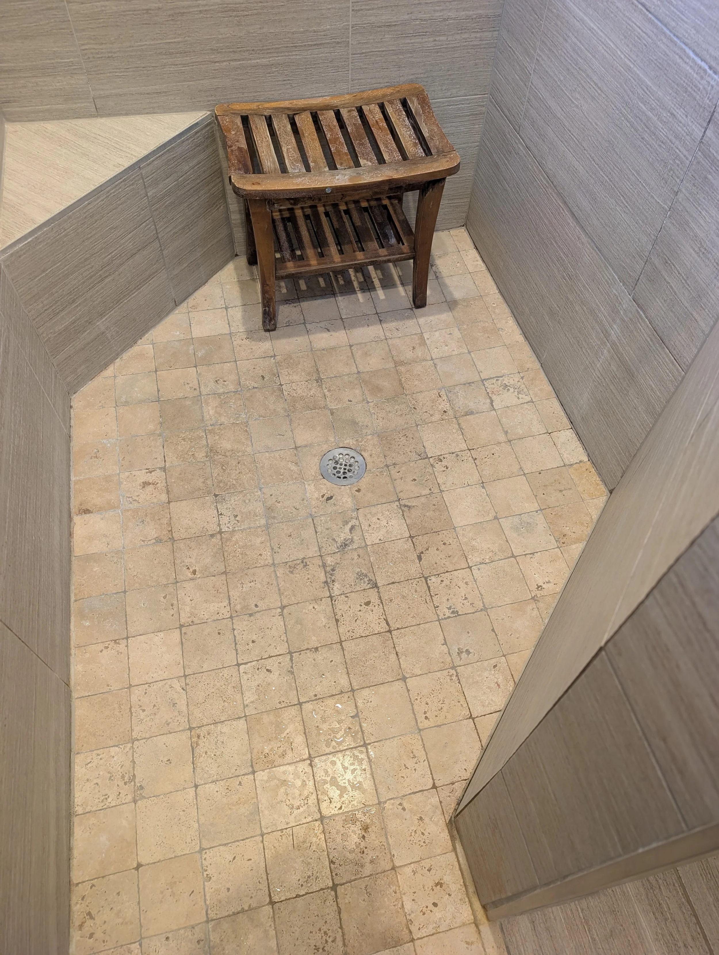 Worn travertine shower floor before tile replacement in Denton, TX. Stained grout and aging tile ready for a full bathroom tile upgrade.