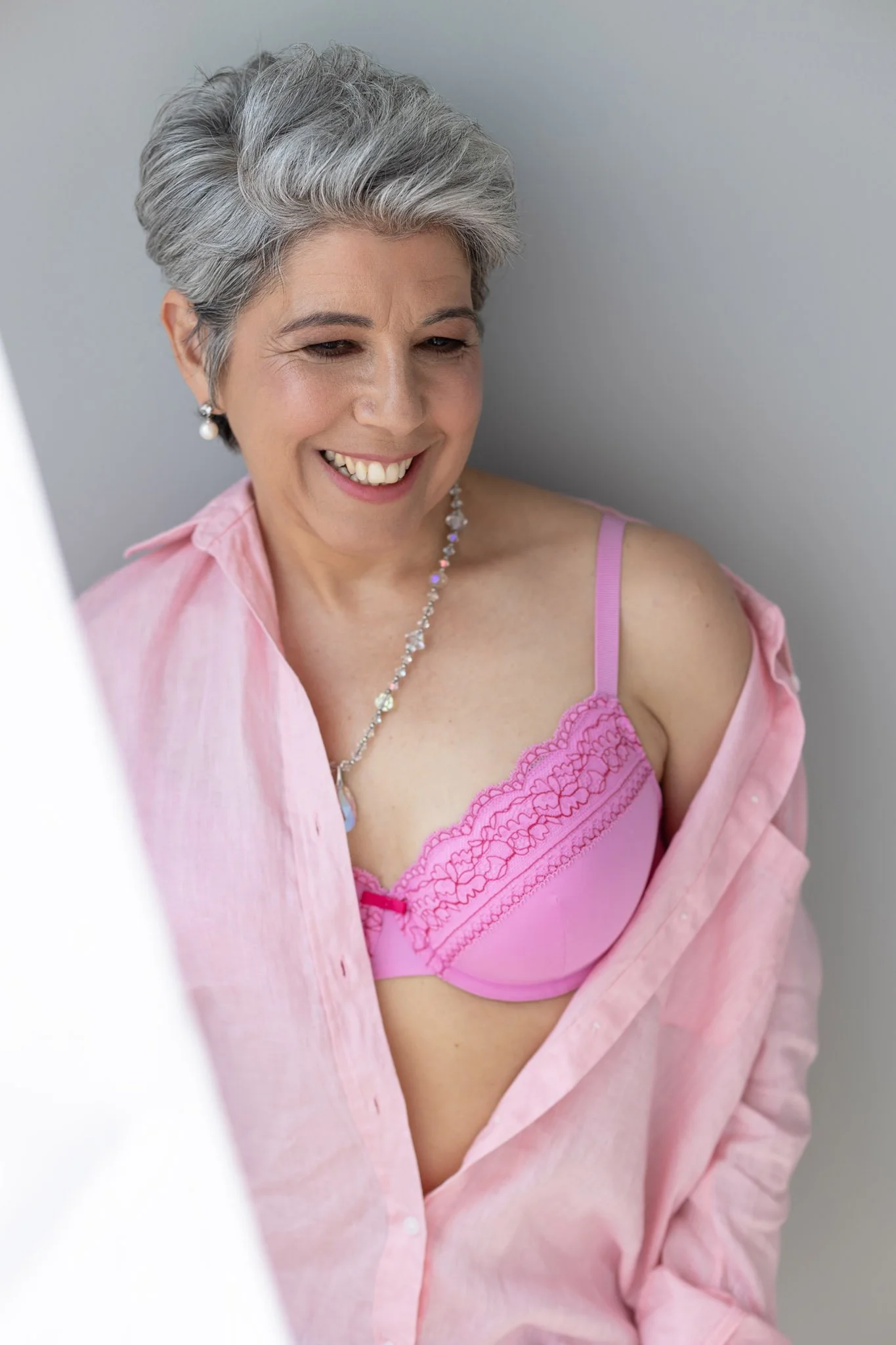 Woman over 40 smiling pink off the shoulder shirt posing for the 40 over 40 campaign Shrewsbury boudoir studio