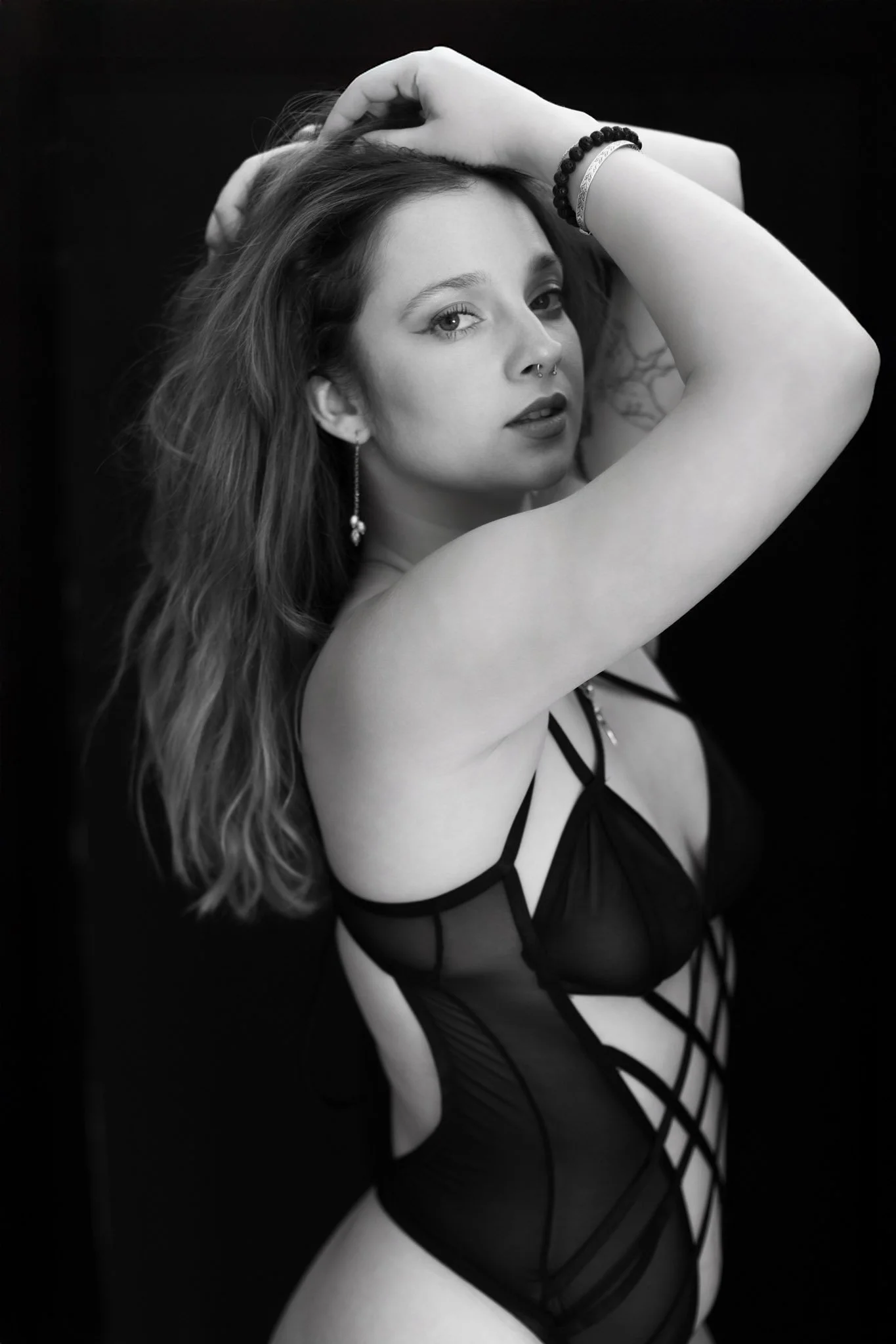 "Woman posing with hands in hair for boudoir session"