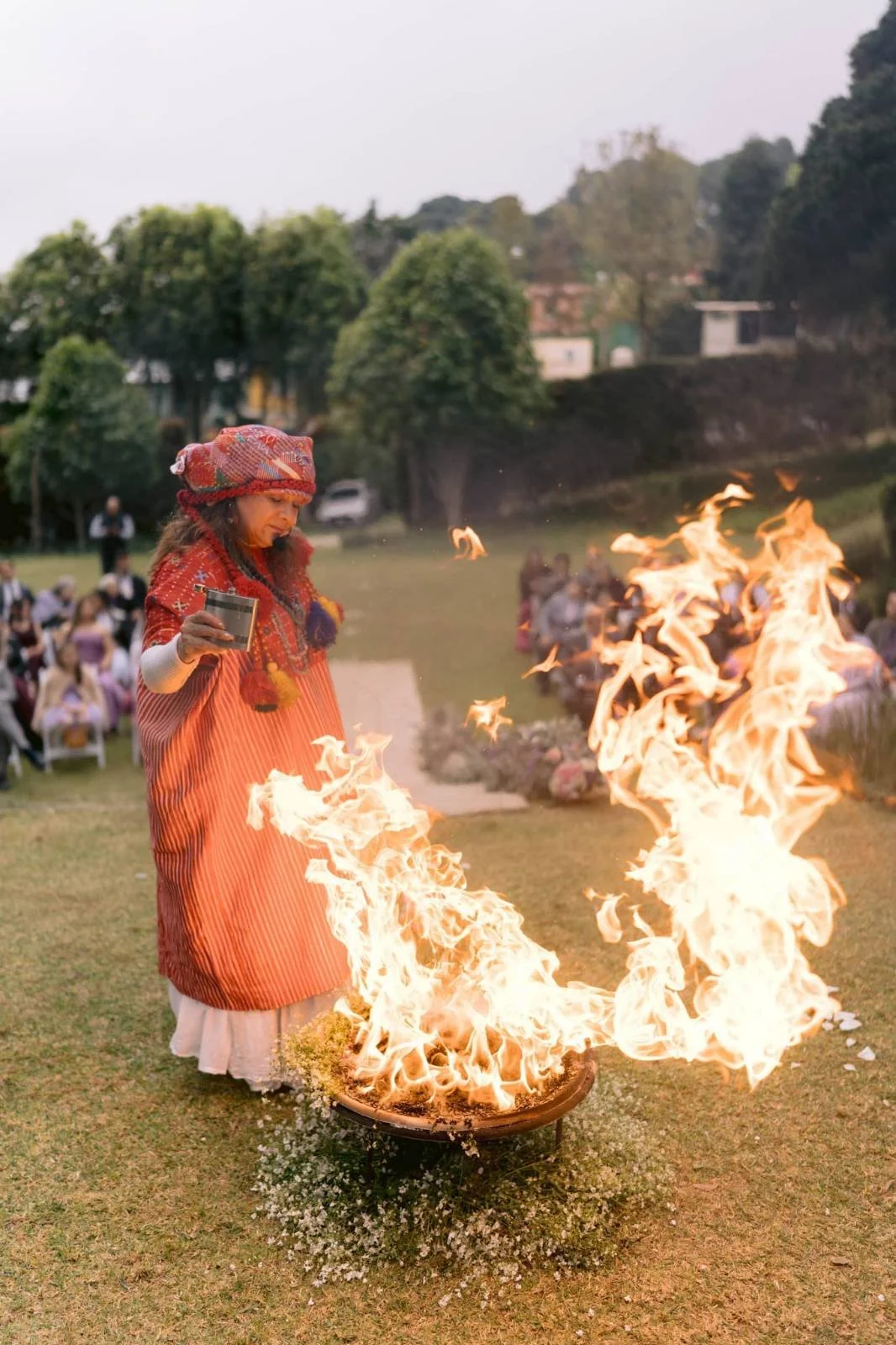 A person performing a fire dance outdoors, surrounded by a group of spectators.