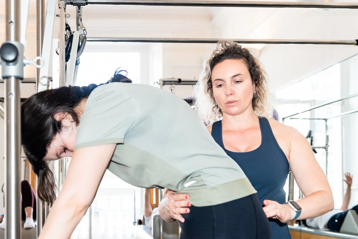 A fitness trainer assisting a woman in a workout at a gym.