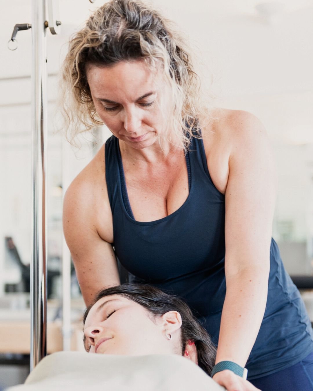 A woman providing abdominal care or massage to a patient lying down in a medical setting.