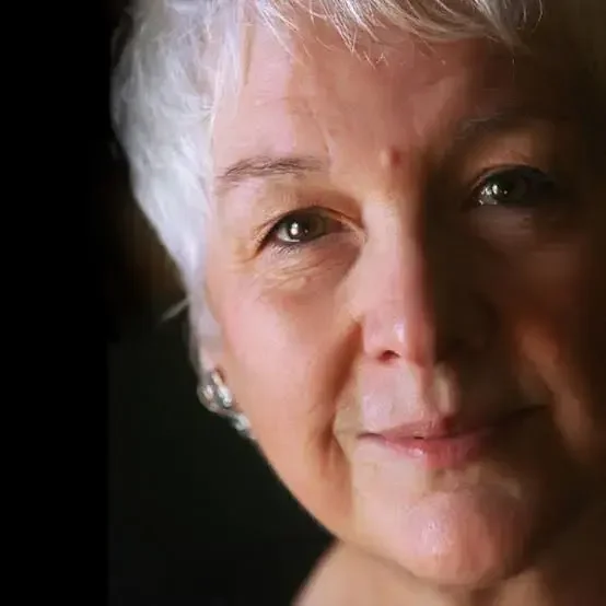 Close-up of an elderly woman with short, white hair smiling slightly.