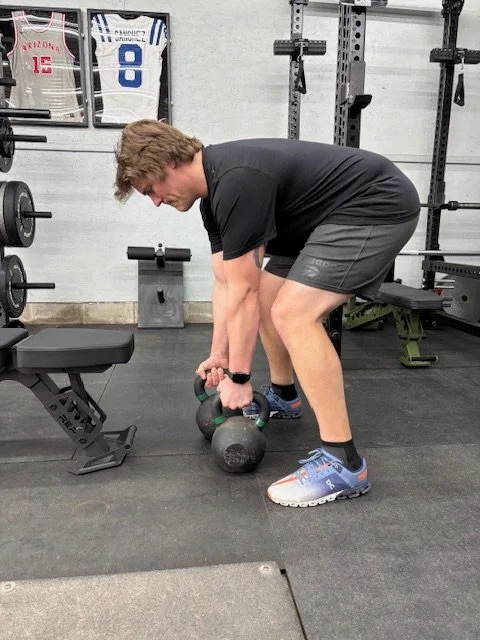 Man performing a deadlift with a kettlebell in a gym.