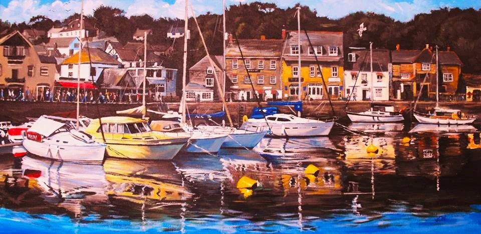 Boats docked along a harbor with colorful buildings in the background on a clear day.