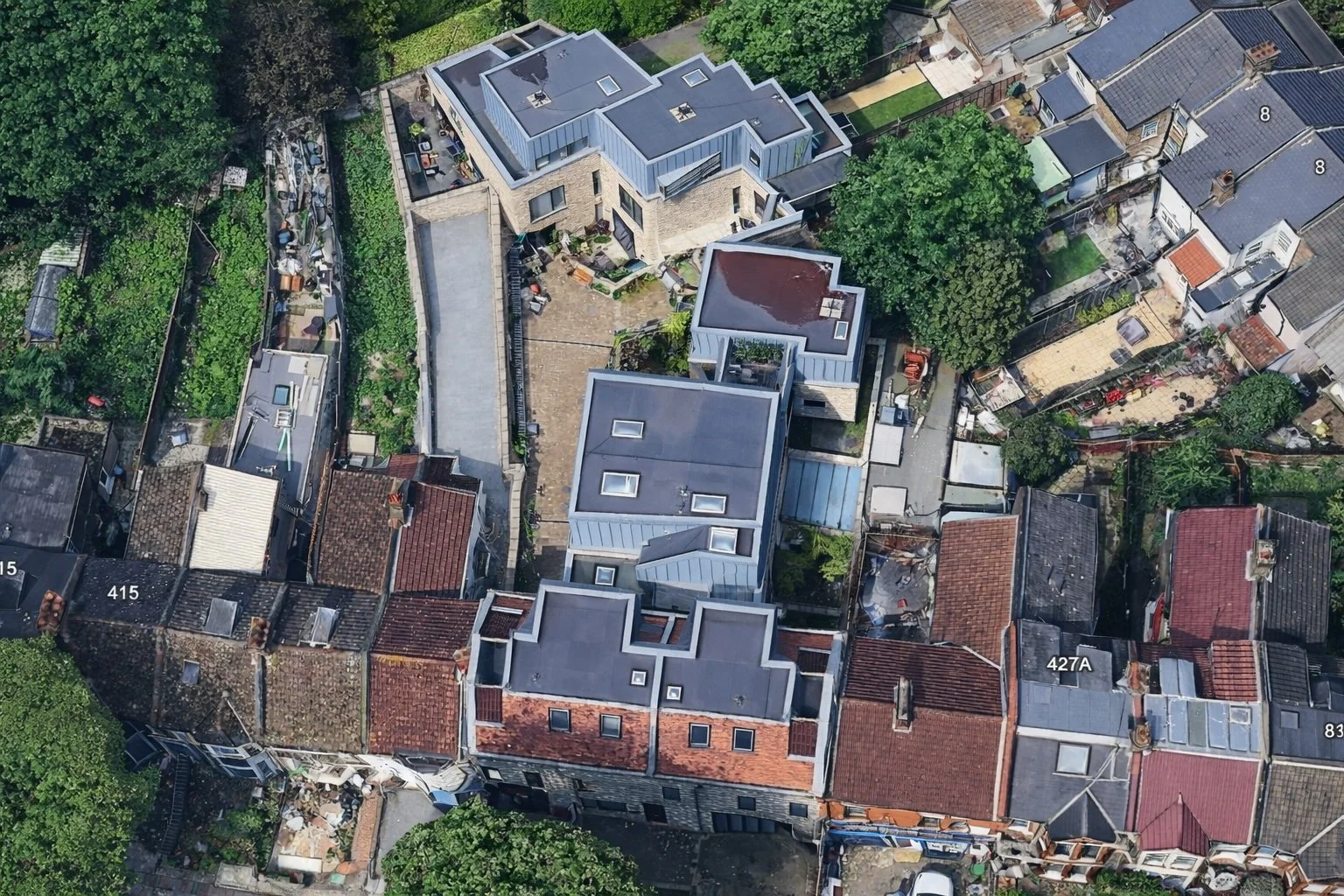 Aerial view of a neighborhood showing a mix of residential buildings, trees, and outdoor spaces in an urban area.