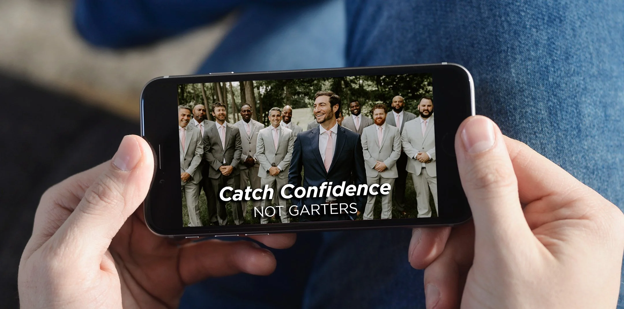 Person holding a smartphone displaying a group of businessmen in suits outdoors, with the overlay text 'Catch Confidence NOT GARTERS' for Michael Strahan Brand.