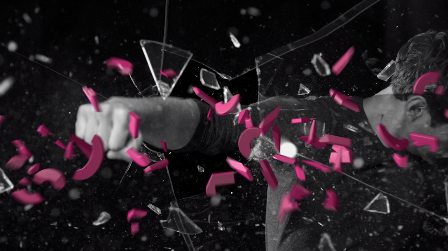 T-mobile TV commercial graphic. A person breaks through a glass surface, with shattered glass and pink debris flying around.
