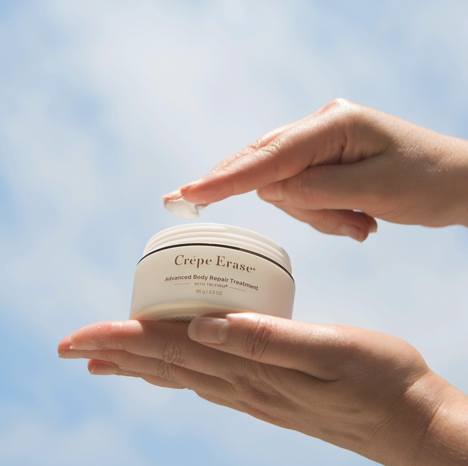 Crepe Erase body lotion product image shot against a blue sky.