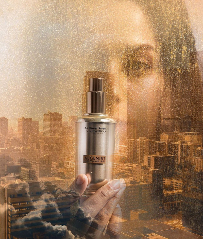 Algenist Skincare AA Barrier Serum bottle with model with city scape overlayed.
