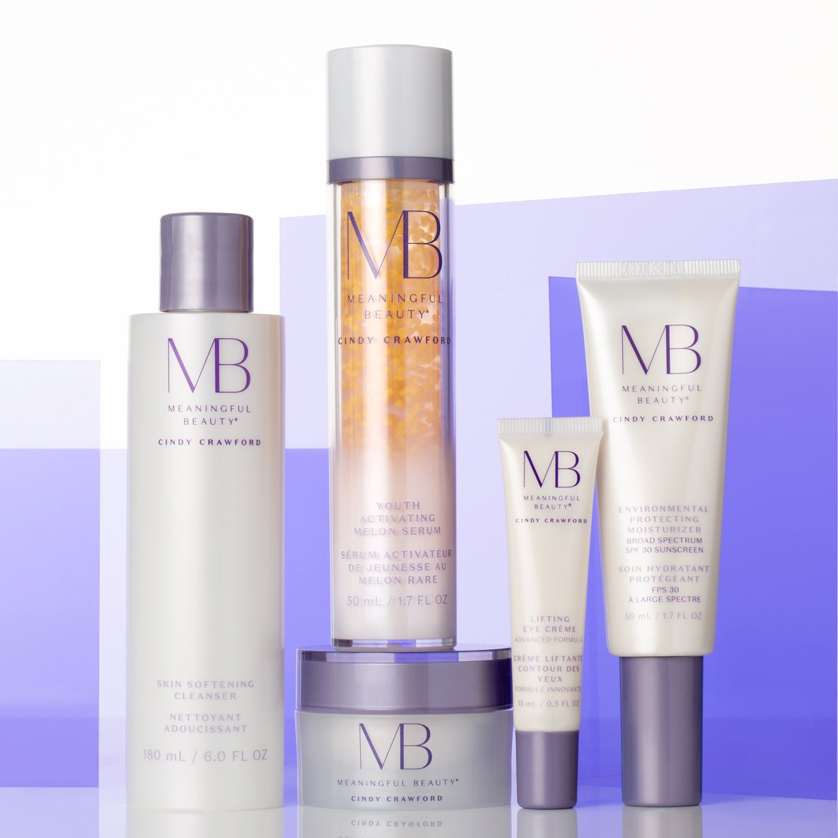 Collection of skincare products from Meaningful Beauty by Cindy Crawford, including cleanser, serum, eye cream, moisturizer, arranged on a purple and white background.