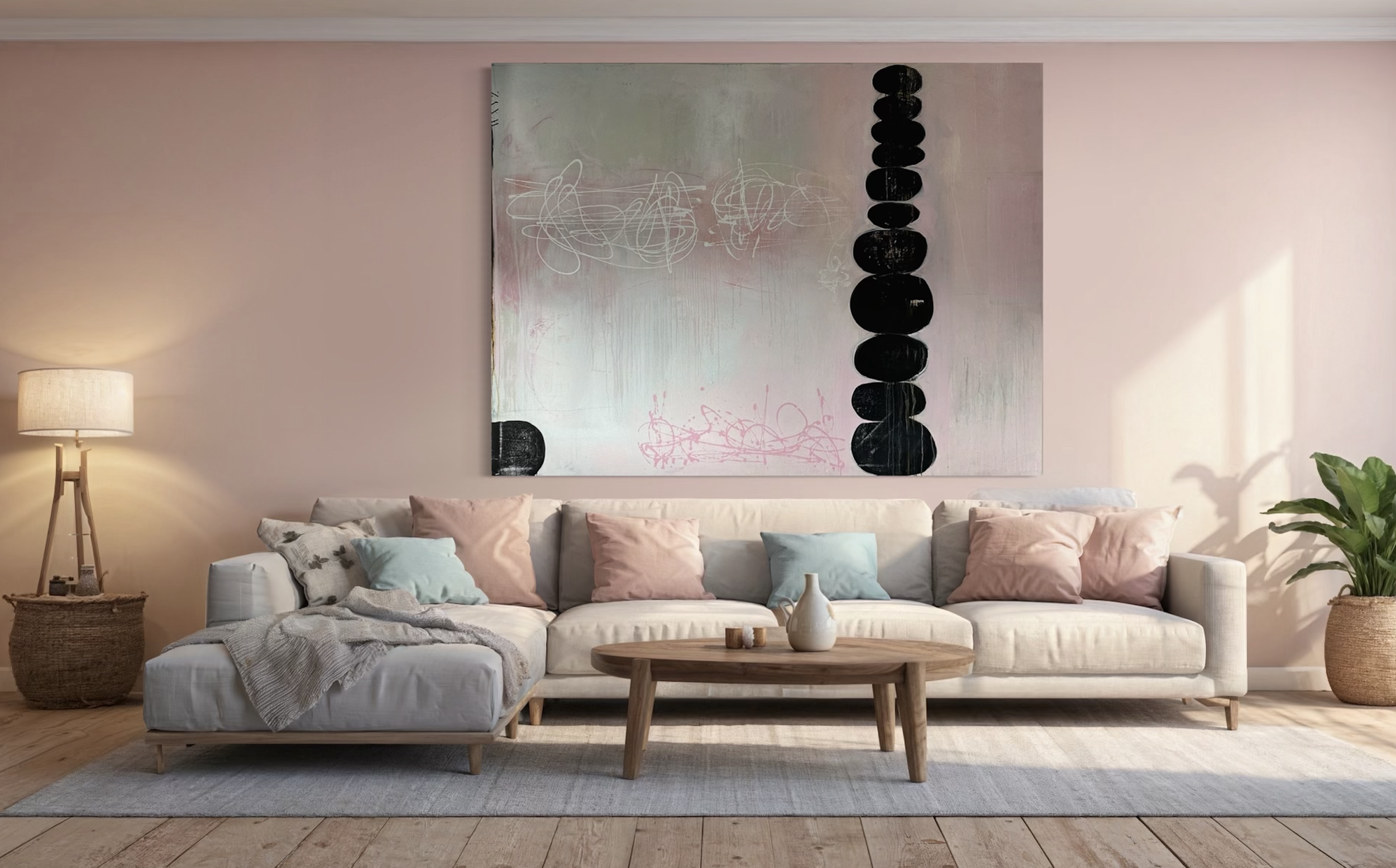 A cozy living room with a large white sofa adorned with pastel pink and blue pillows. A wooden coffee table with a white vase and small decor items sits in front. Behind the sofa, there's an abstract painting with soft pastel shades and black circula