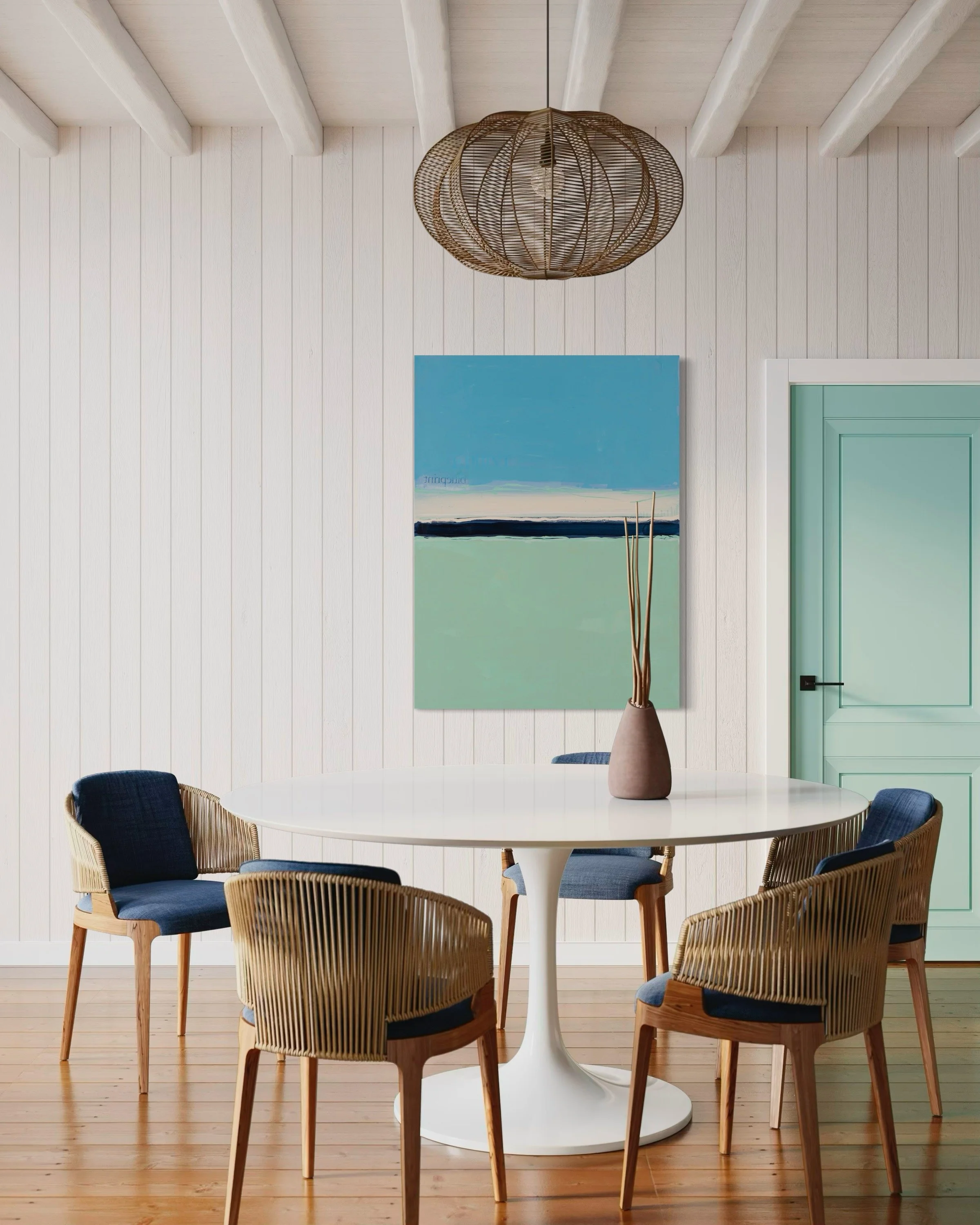 A dining room with a white round table, five wicker chairs with dark blue cushions, a vase with tall sticks, a pastel green door, a large abstract landscape painting, and a rattan pendant light.