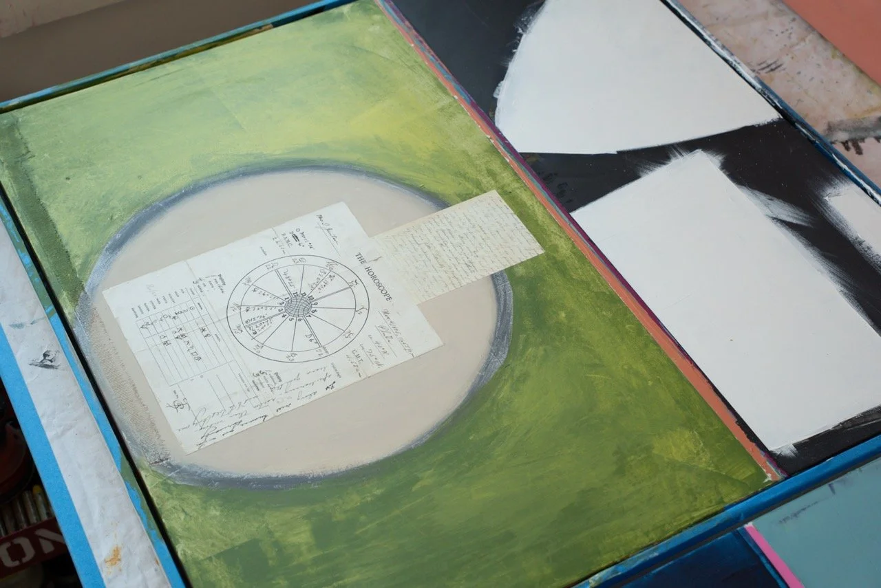 Open box with artwork on the inside and papers, including a diagram and handwritten notes, on the surface.