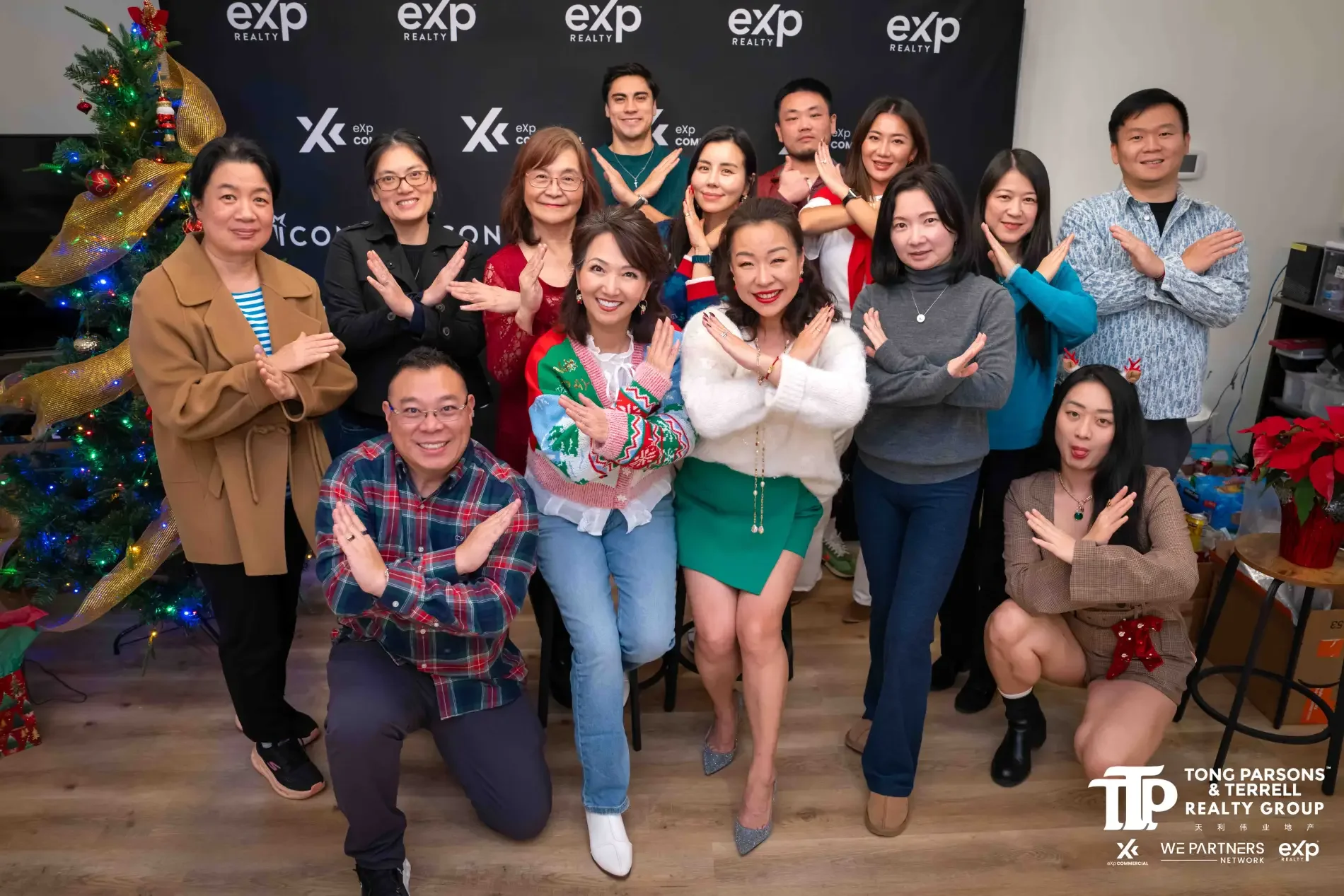 A group of people posing for a photo at a holiday celebration, with a Christmas tree on the left decorated with colorful lights and ribbon. The backdrop has the logos of 'exp Realty' and 'xcp.com', and the bottom right corner contains the logos and text of Tong Parson's & Terrell Realty Group, WE Partners, and EXP Network.