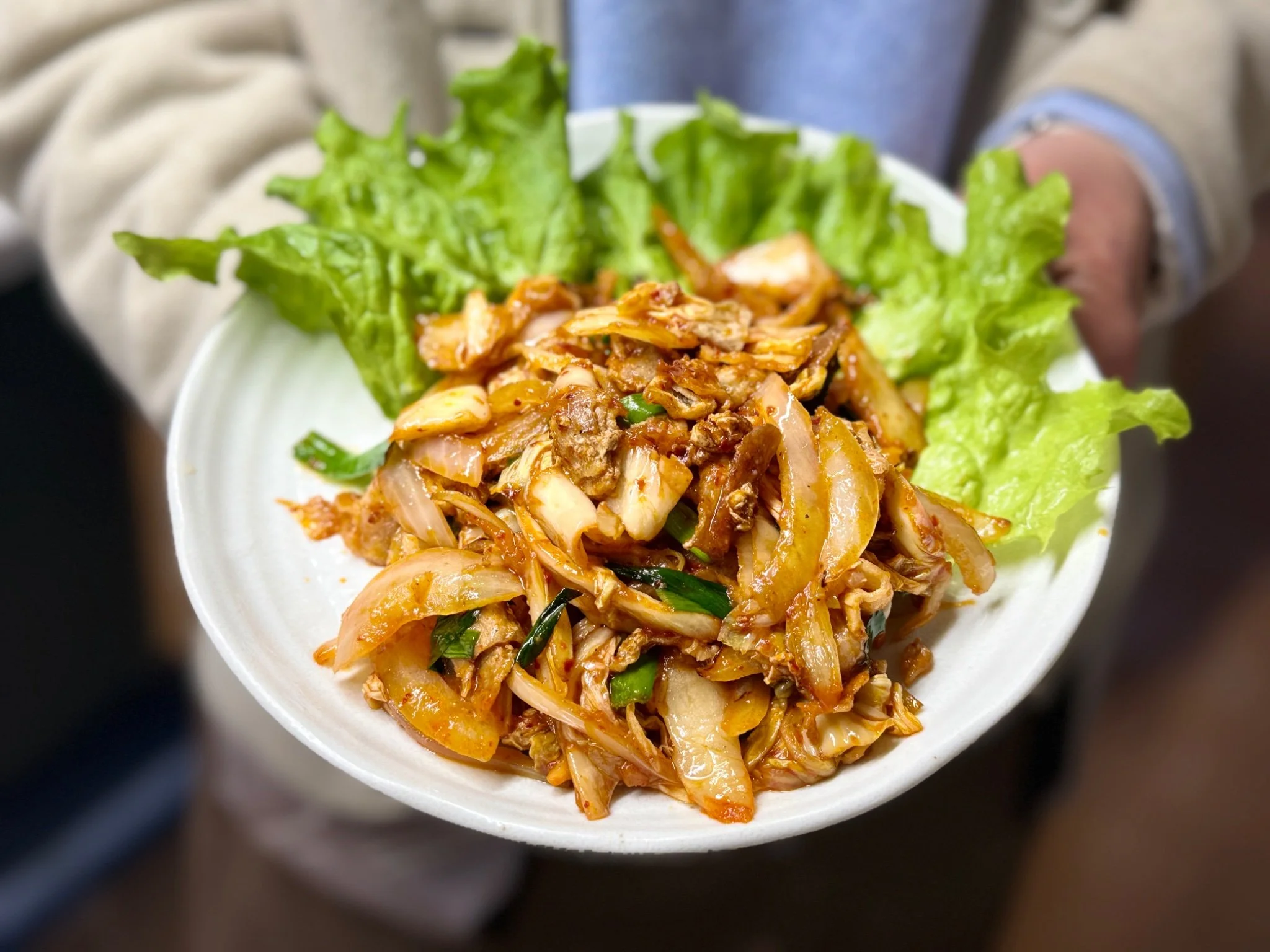 A white plate with a fried rice-like dish on top of lettuce