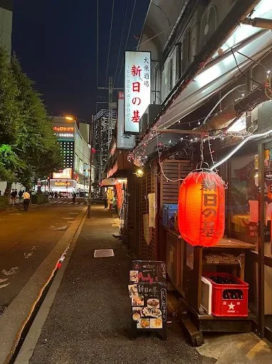 A street in the nighttime entertainment district. Red lanterns and signs are visible.