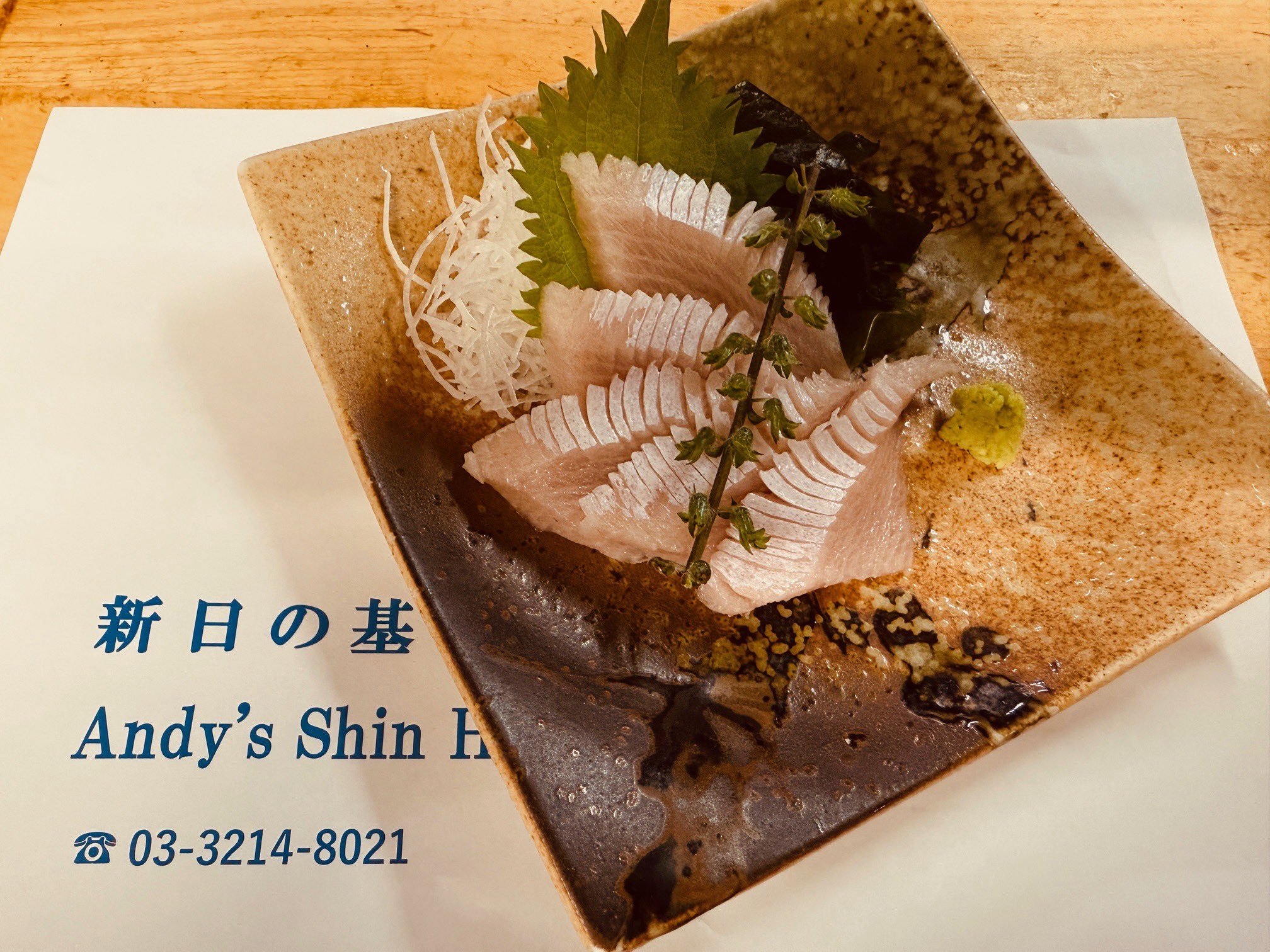 A plate of assorted sashimi garnished with shiso leaves and wasabi
