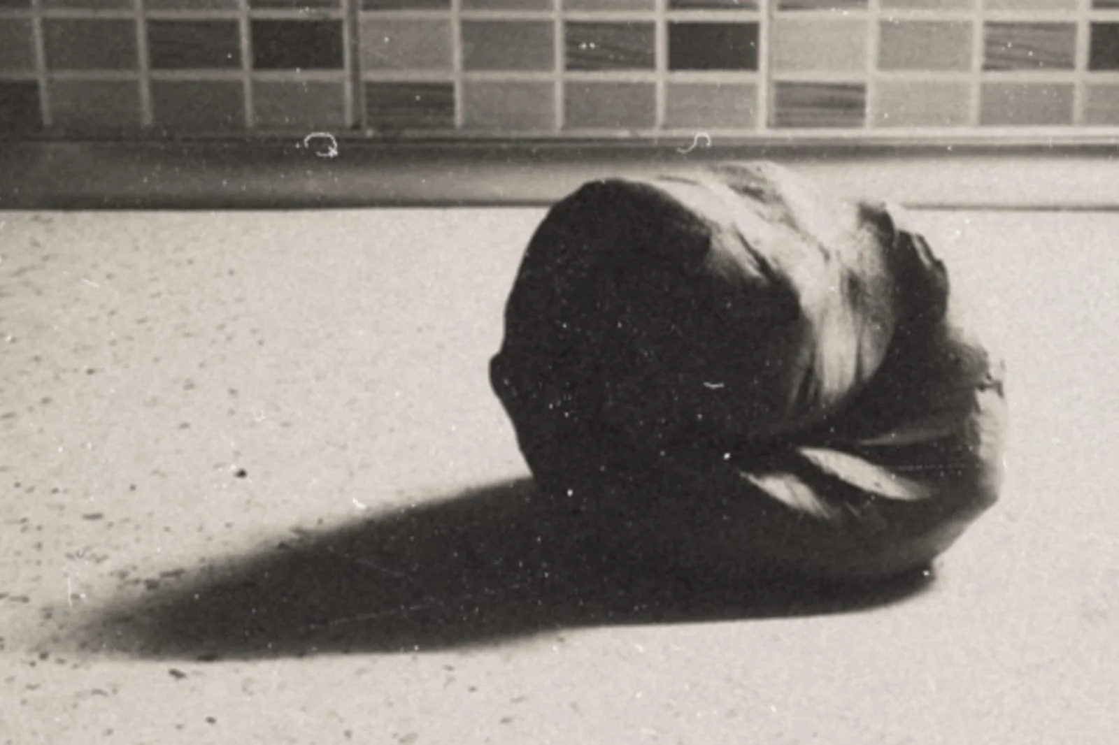 Black and white photograph of a clay kneaded on the workbench casts a long shadow on the bench.