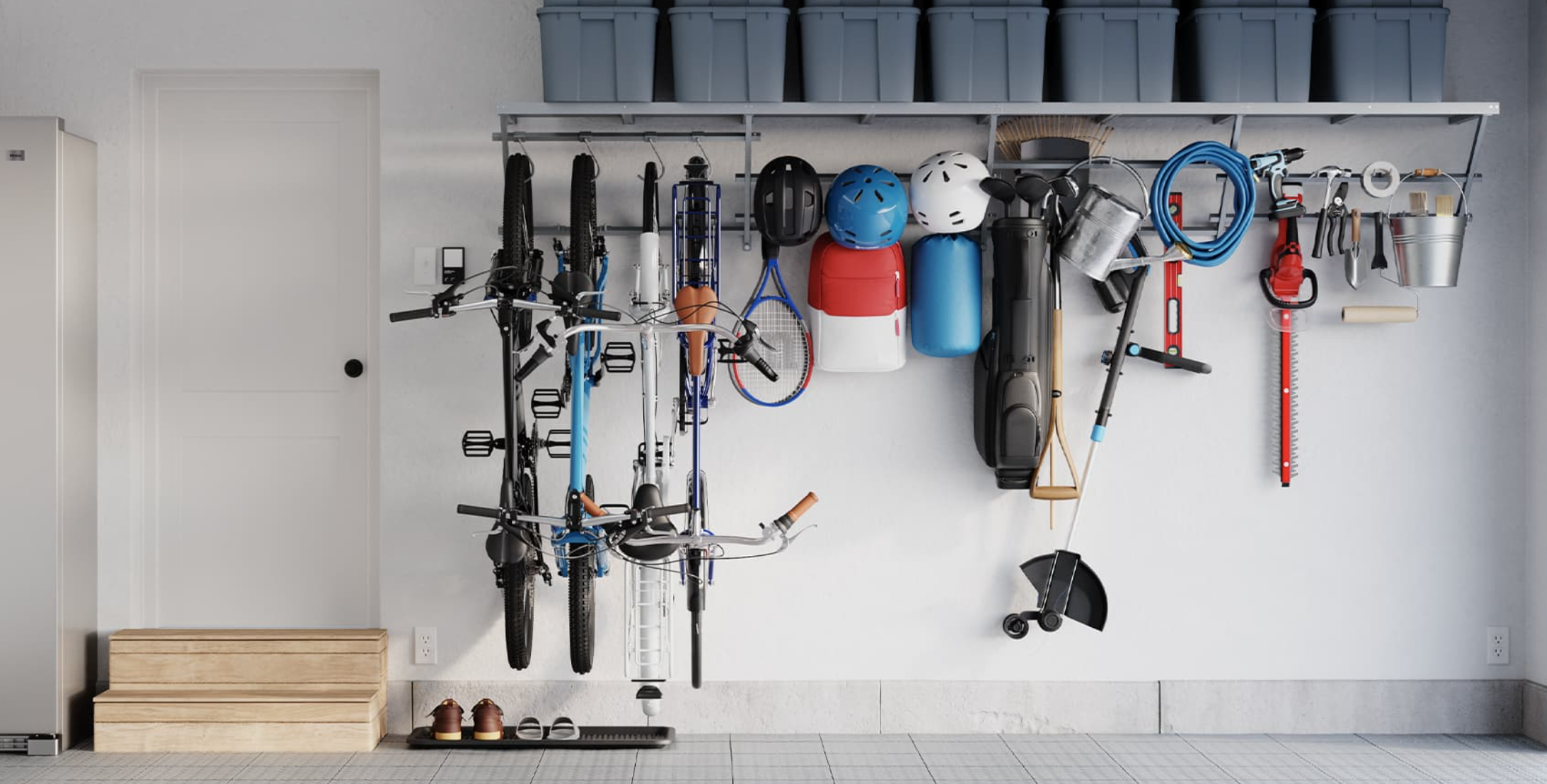 Garage wall with organized bike, helmets, sports equipment, gardening tools, and storage bins.