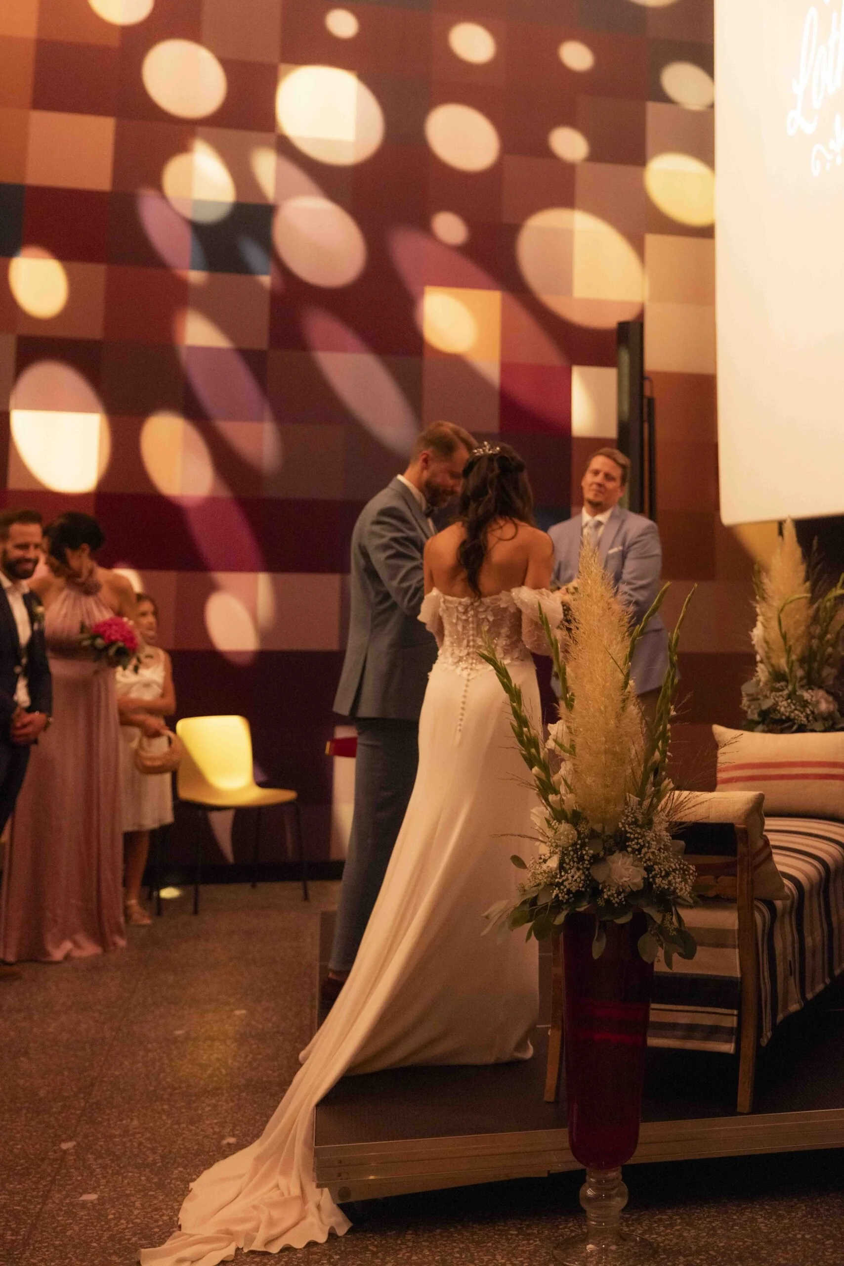 Menschen bei einer Hochzeitszeremonie, Hochzeitskleider, Blumen und Dekorationen im Veranstaltungsraum.