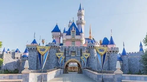 Walt Disney Castle at Disneyland with blue spires and flags.