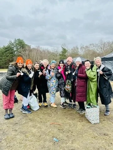 Outdoor fitness in Cranleigh. Group of people outdoors on a cloudy day, bundled in warm clothing, smiling and posing together.