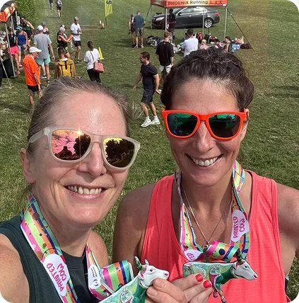 Two women wearing running medals.