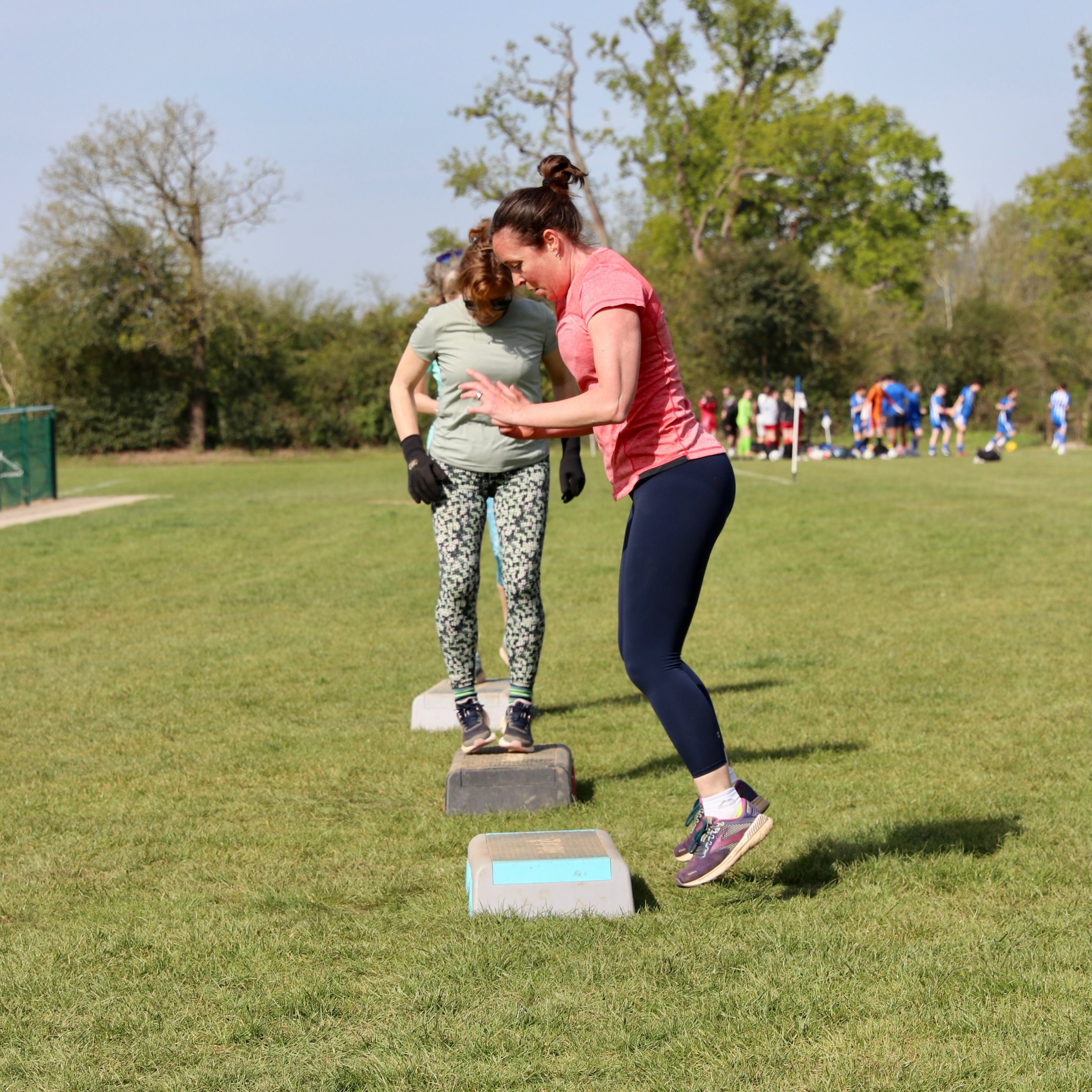 Two females step exercising outside.