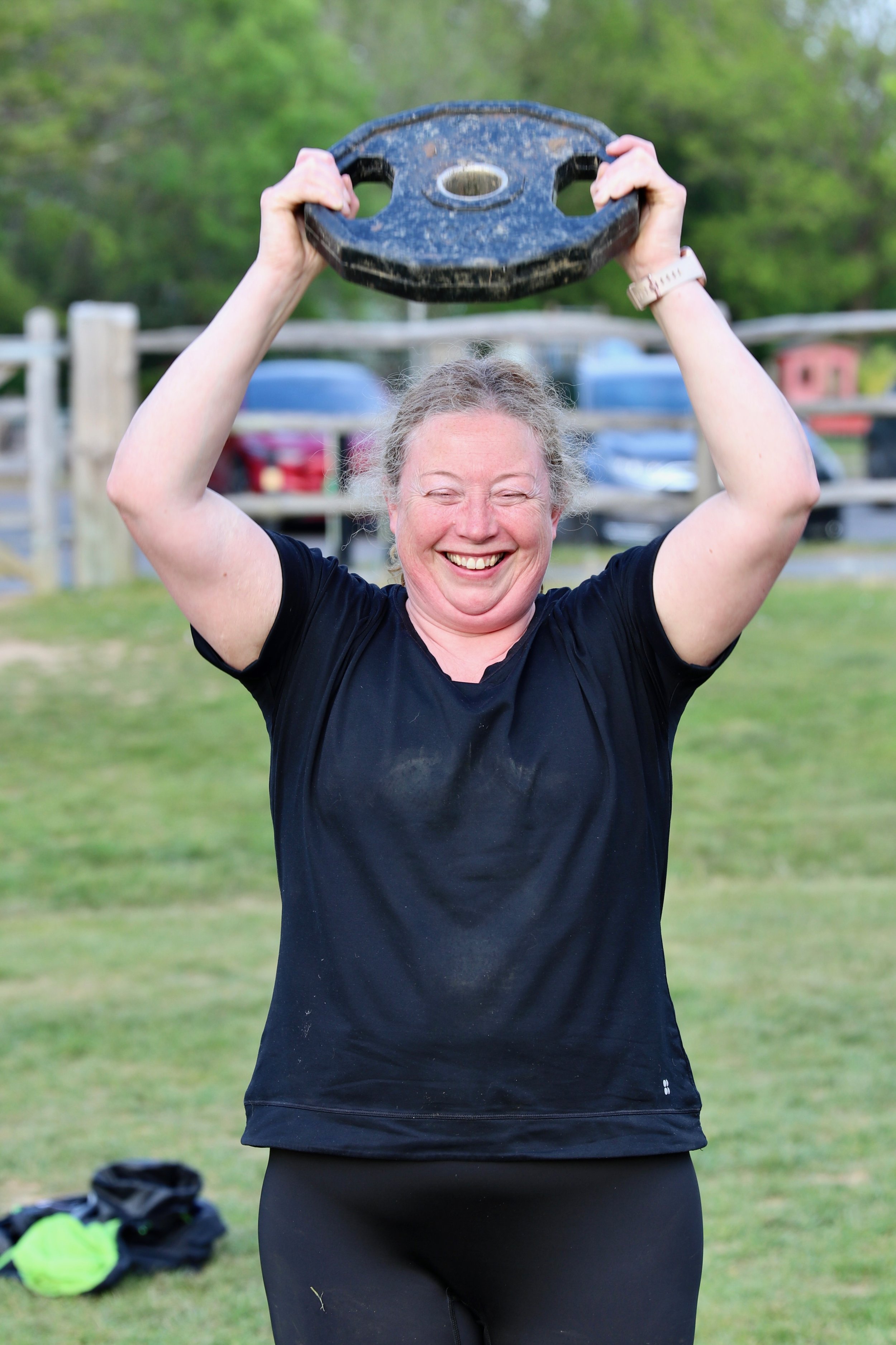 Happy female exercise group member lifting weights.