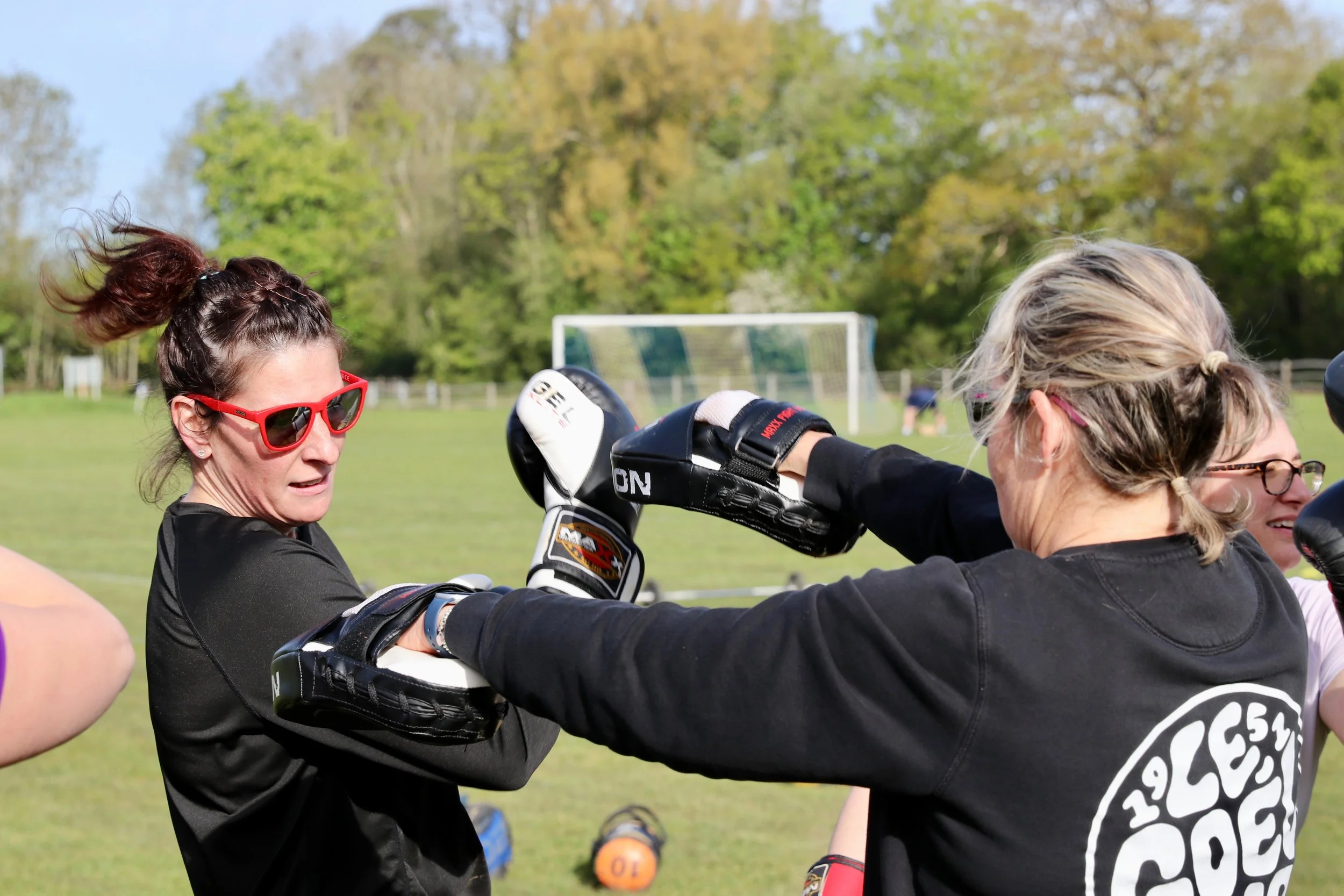 Two female exercise group members boxing.