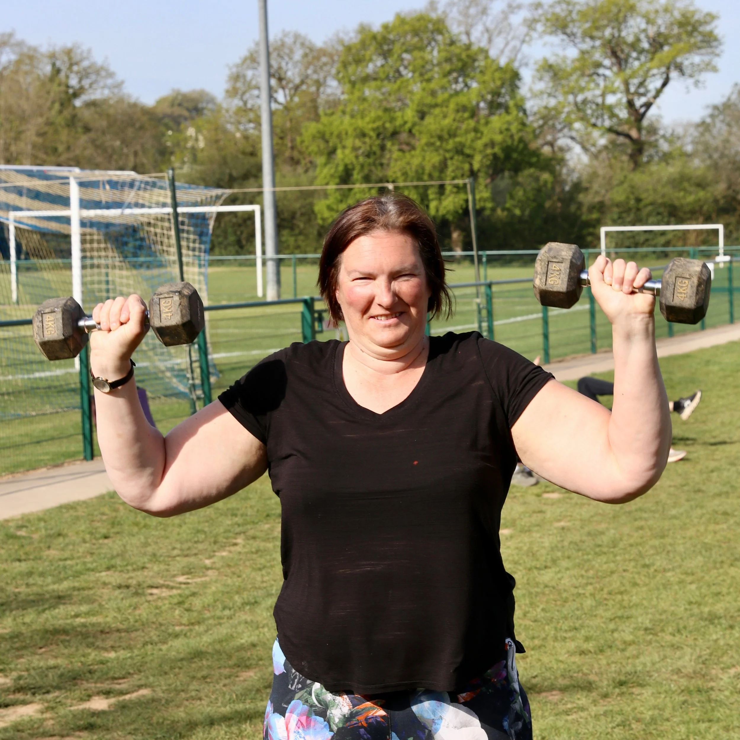 Female exercise group member holding weights.