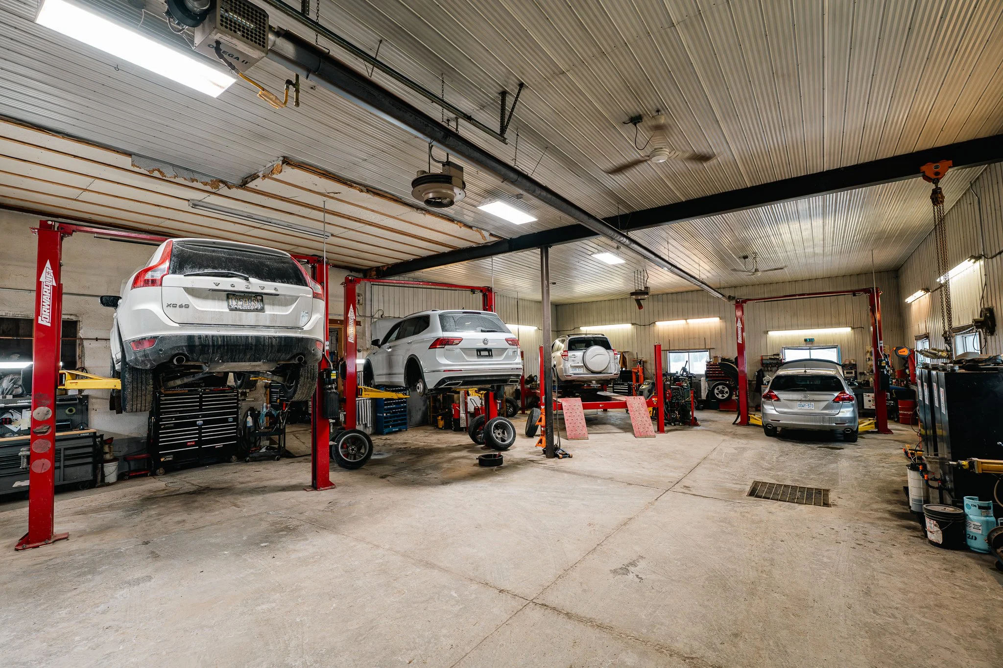 Auto repair shop with four cars on hydraulic lifts and one on the ground, various tools, and equipment around the space.