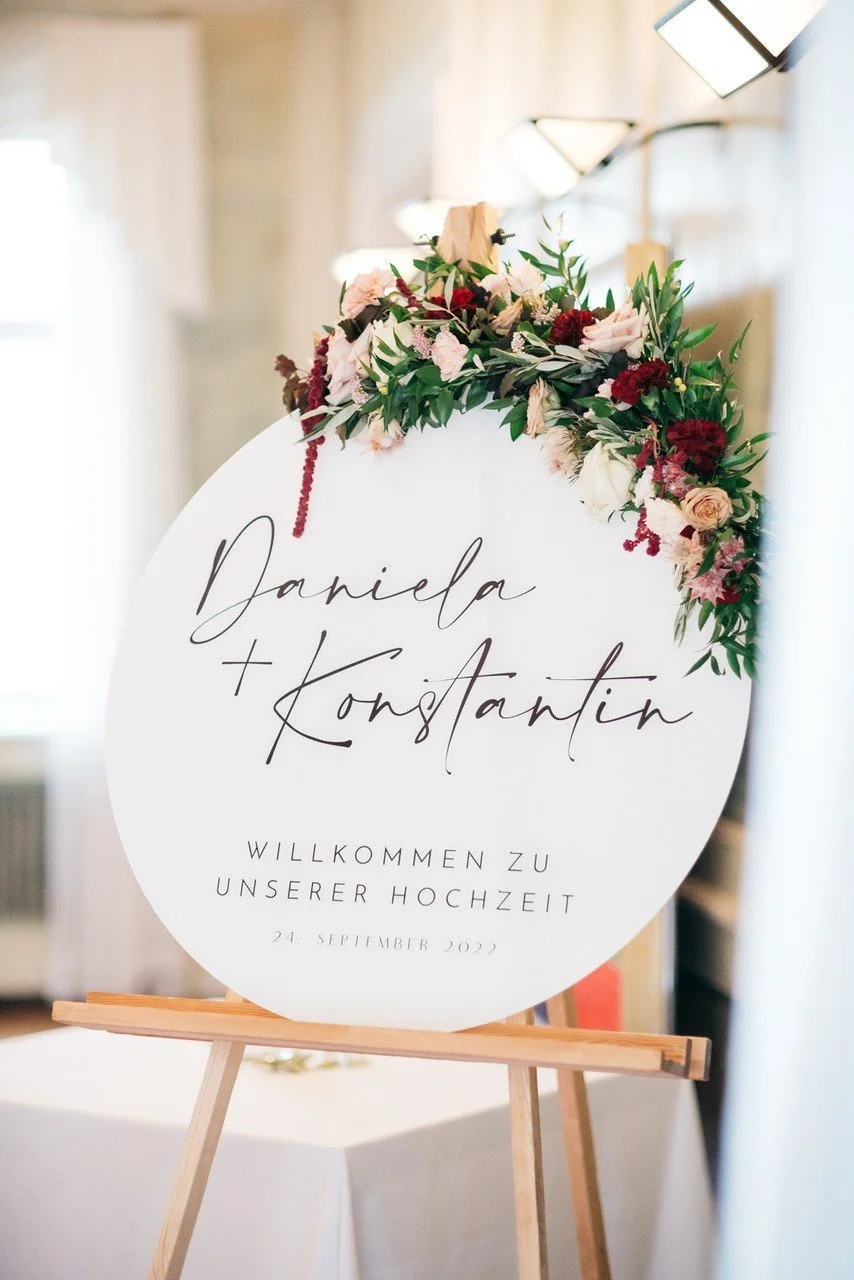 Hochzeitsschild mit Blumen, begrüßt Gäste zur Hochzeit von Daniela und Konstantin am 24. September 2022.