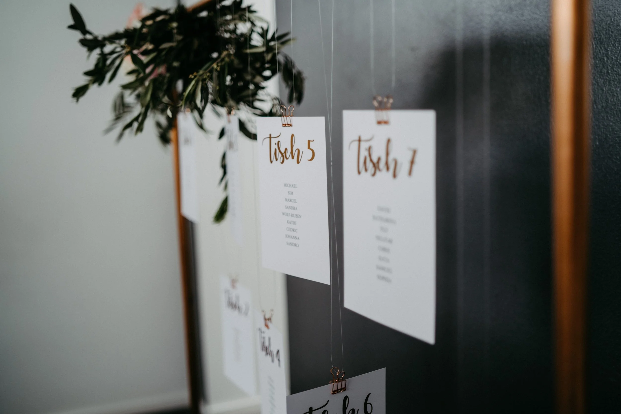 Wunschliste für Tische, Karte mit Tischnummern und Namen, an einer Wand hängt eine rote Rose