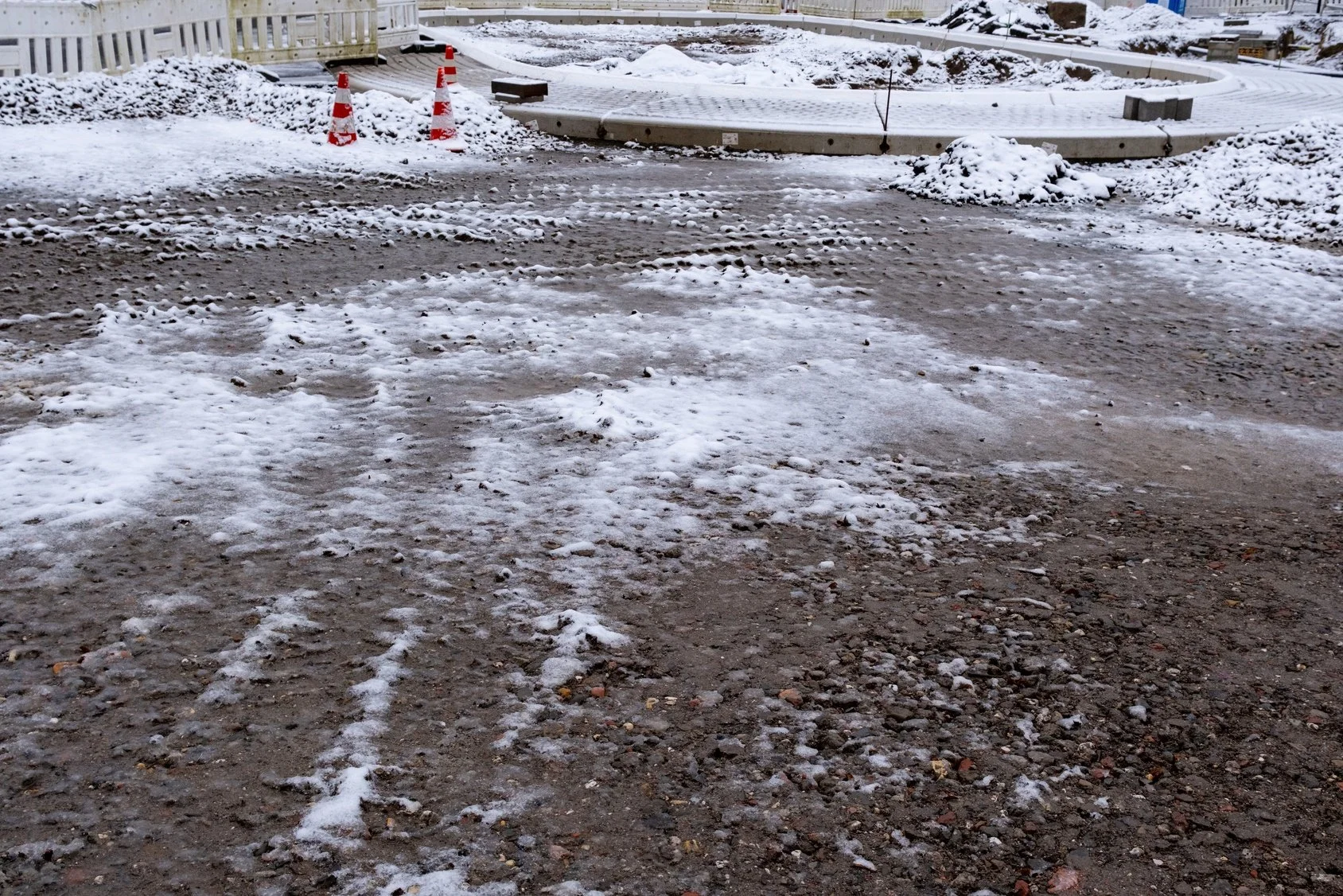 Construction site with melting snow and safety cones in winter