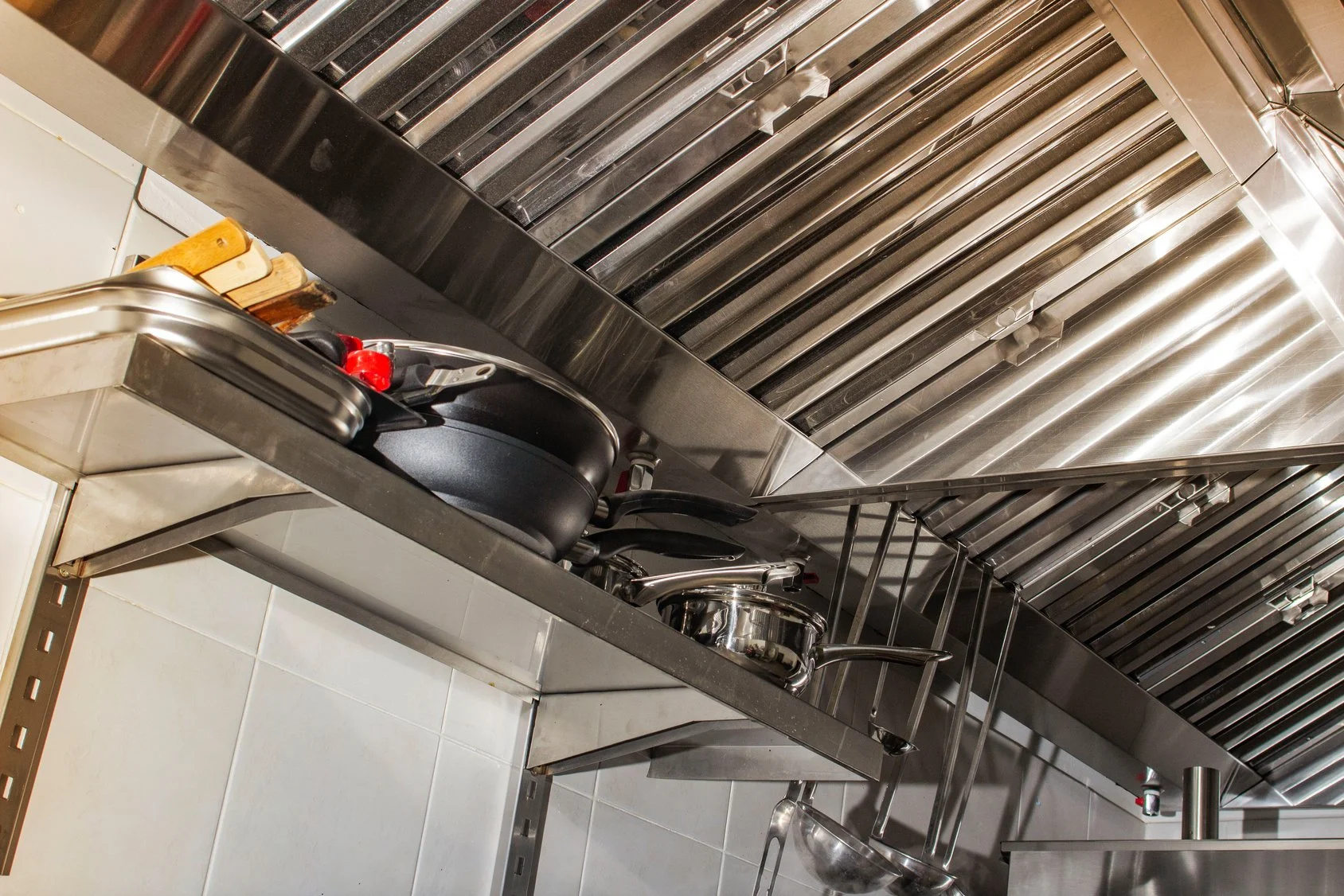 Stainless steel exhaust hood and filters above a commercial kitchen line