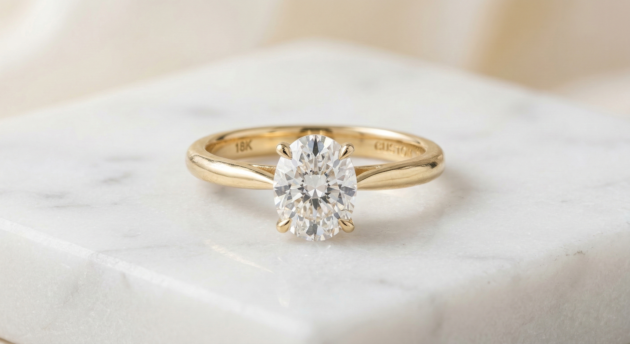 Bague solitaire ovale en or jaune sur marbre blanc