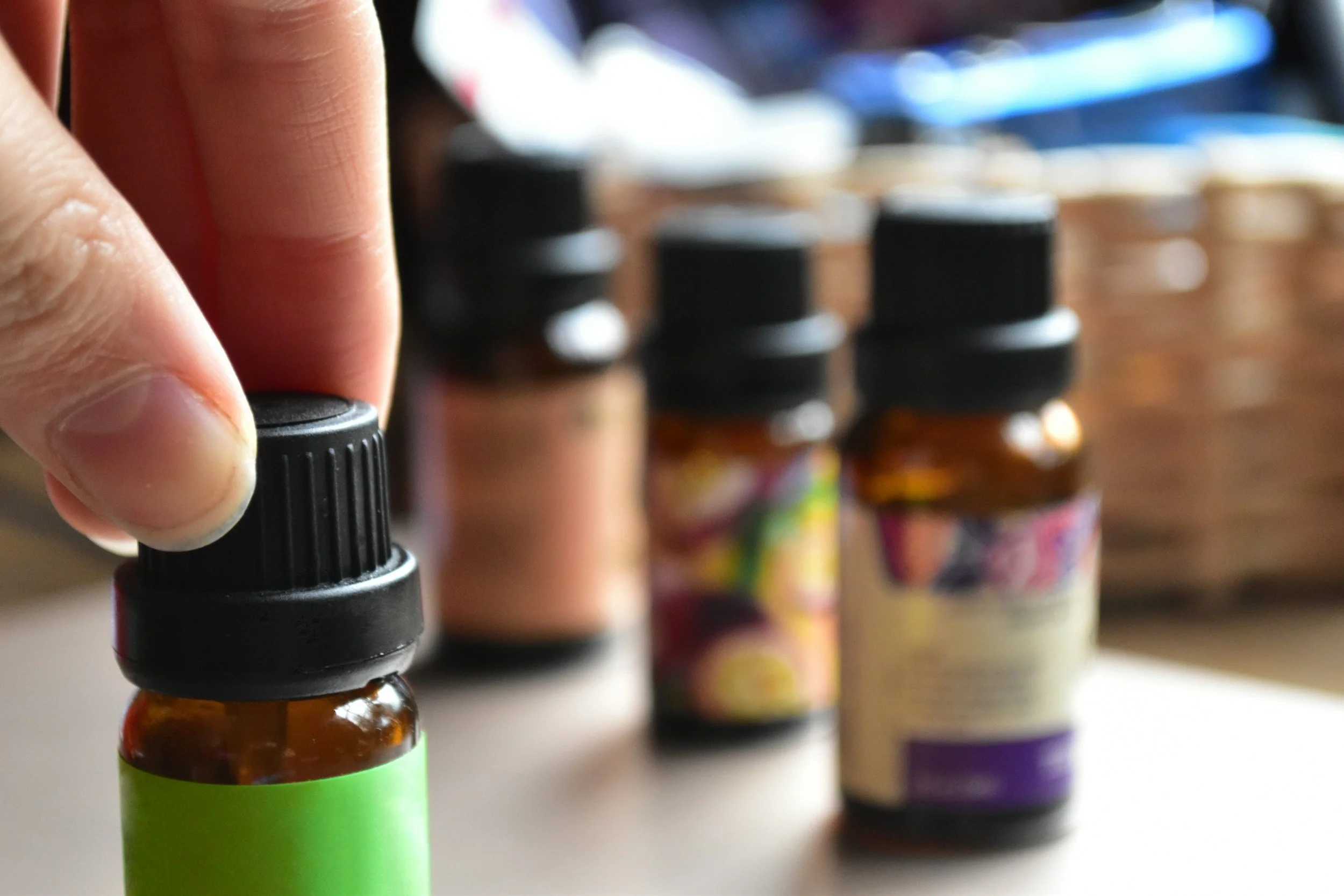 A person holding a small brown bottle with an eye dropper lid, with several other small brown bottles in the background.