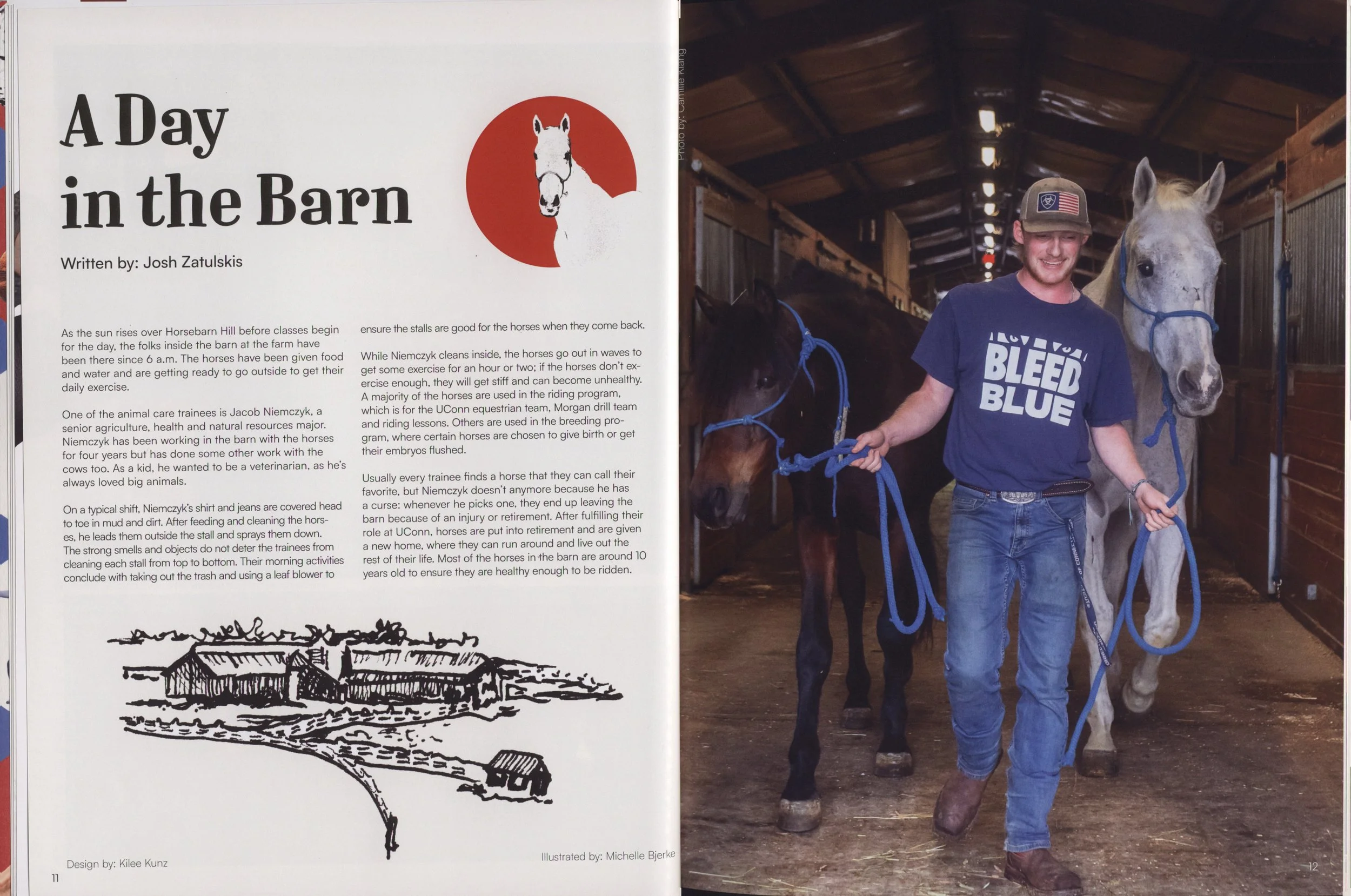A young man wearing a baseball cap and a blue T-shirt is standing in a barn, holding the reins of a white horse with a blue halter. The barn has wooden walls and a high, peaked roof with lights hanging from the ceiling. There is a second horse visible behind the man, and the atmosphere appears warm and rustic.