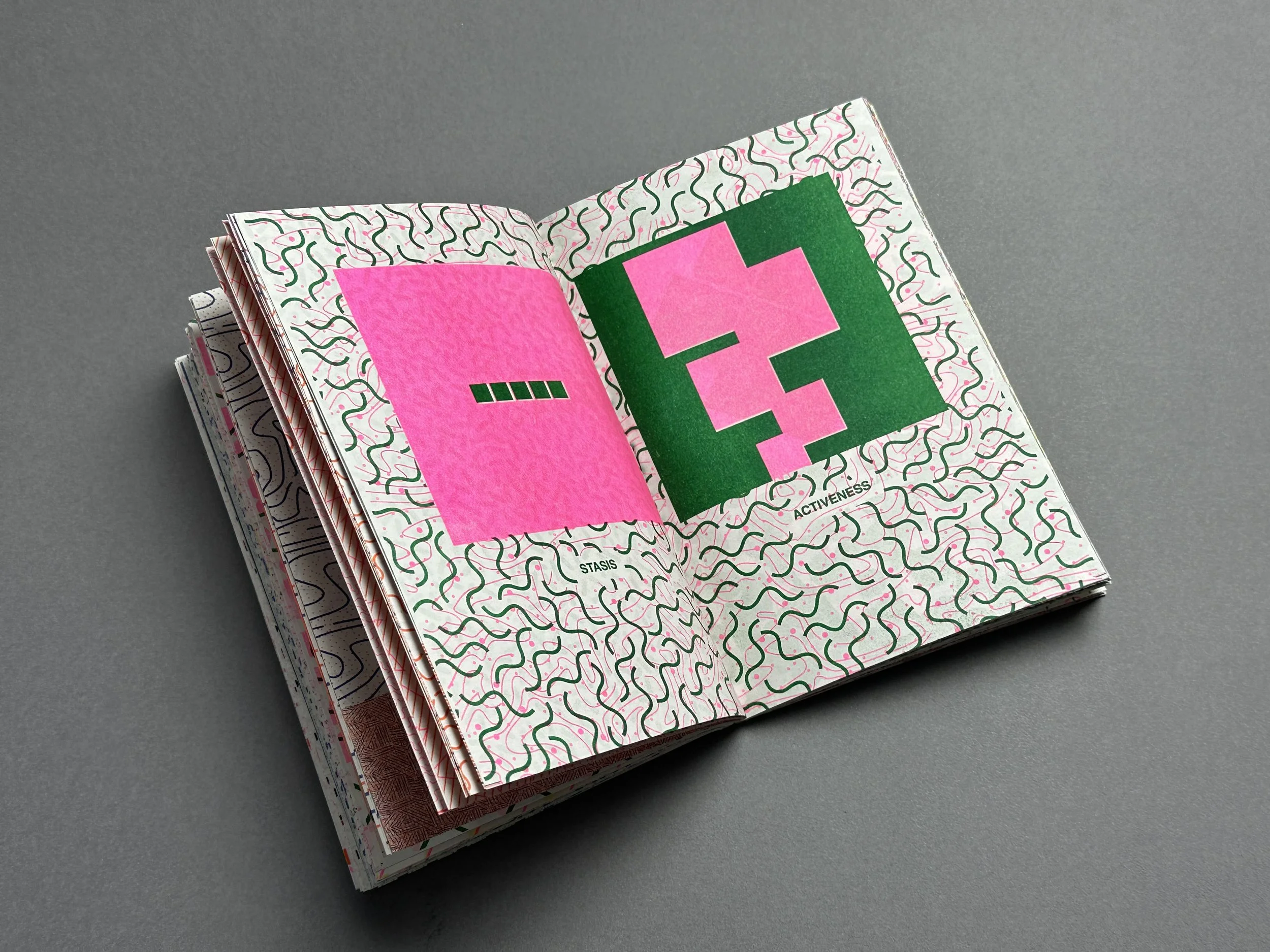 Open colorful booklet with geometric and abstract patterns, on a gray background.