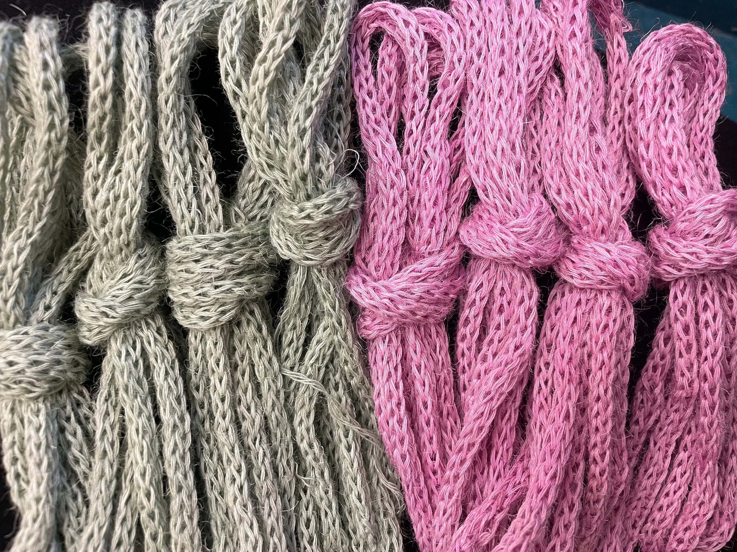 Close-up of knitted sweaters, one in beige and another in pink, with a looped pattern.