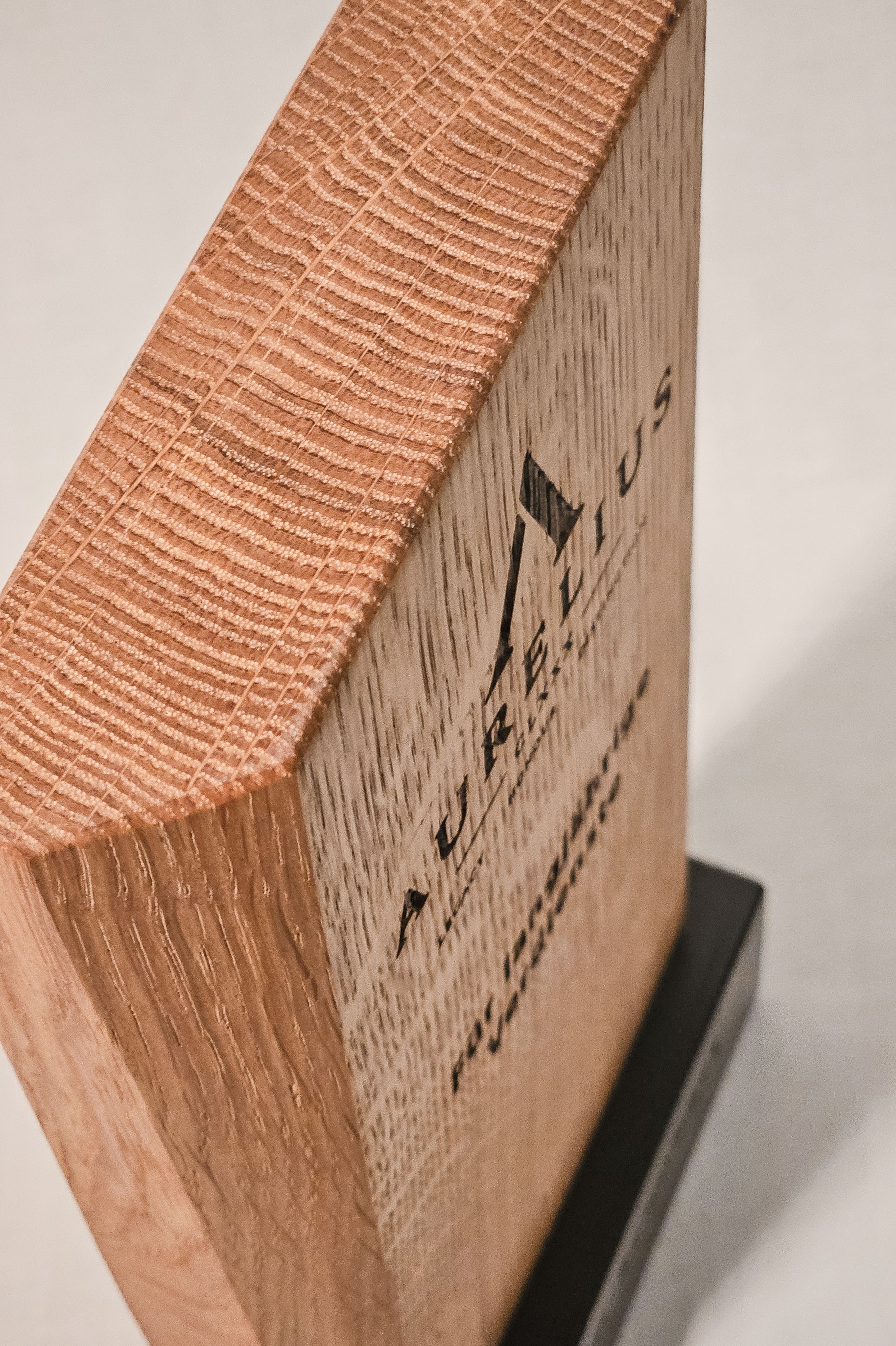 Detailansicht der präzisen Gravur und Holzmaserung eines individuellen Massivholz-Awards aus Eiche für Mitarbeiterjubiläen in Unternehmen sowie Ehrungen langjähriger Mitglieder und sportlicher Erfolge in Clubs.
