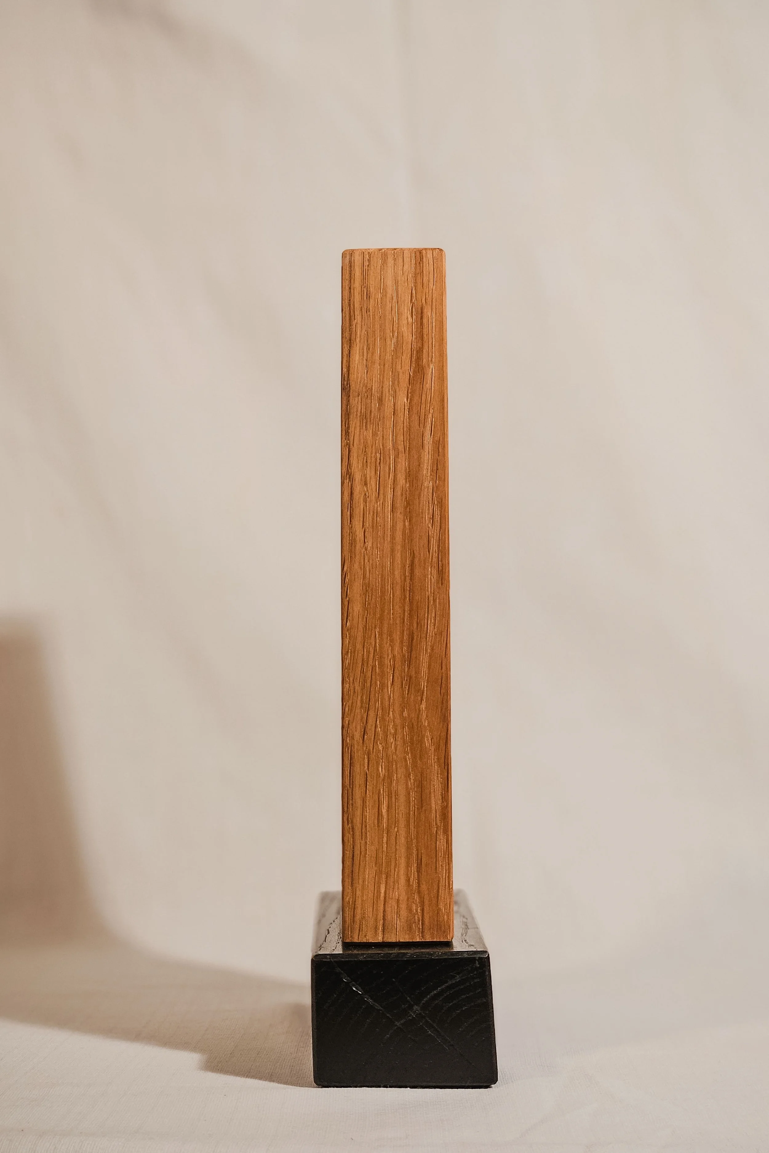 Skulptur eines rechteckigen Holzblocks auf schwarzem Würfel