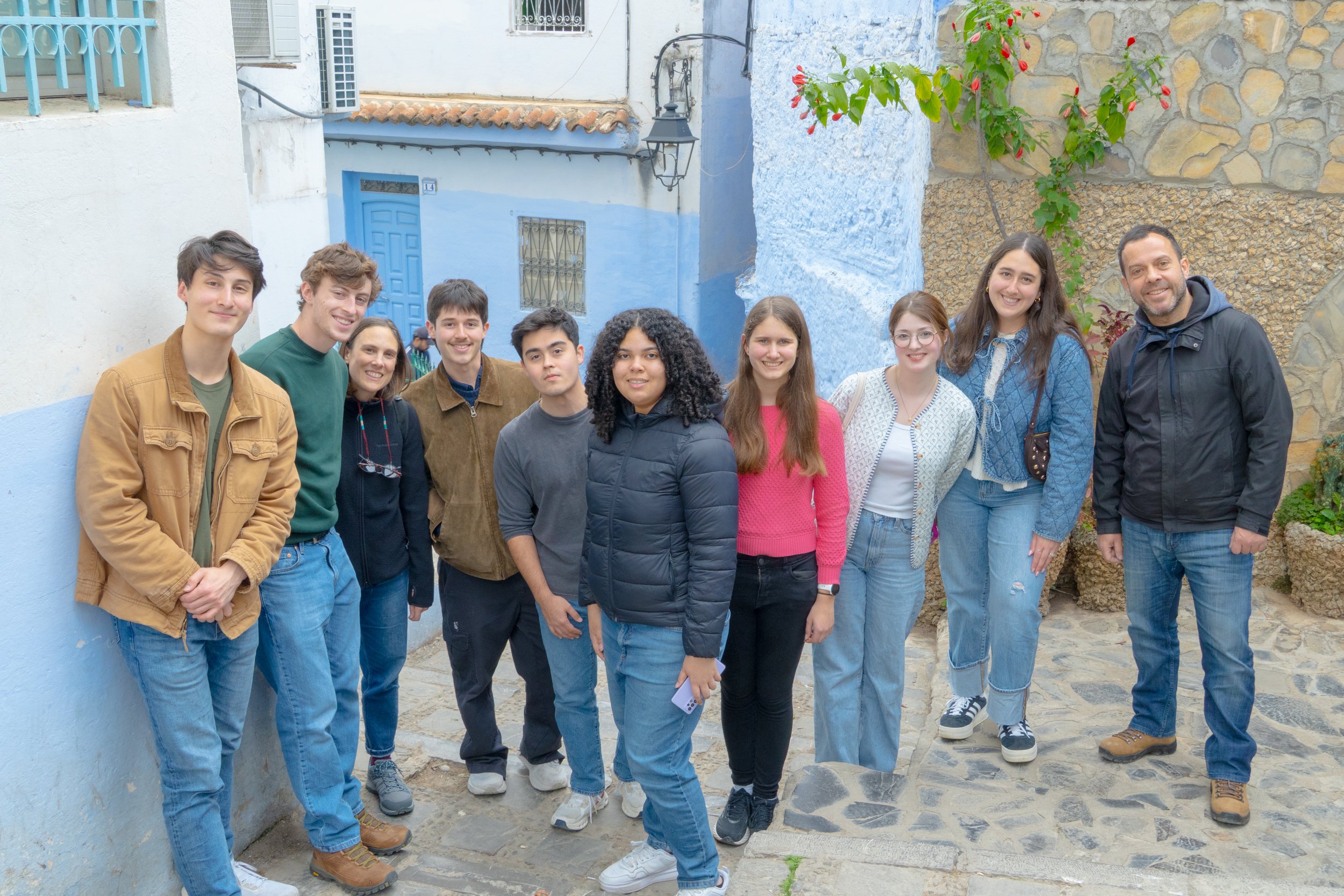 A variety of spices and herbs in bowls and containers at a market, including yellow, orange, red, and brown powders, dried herbs, and a blue spice.