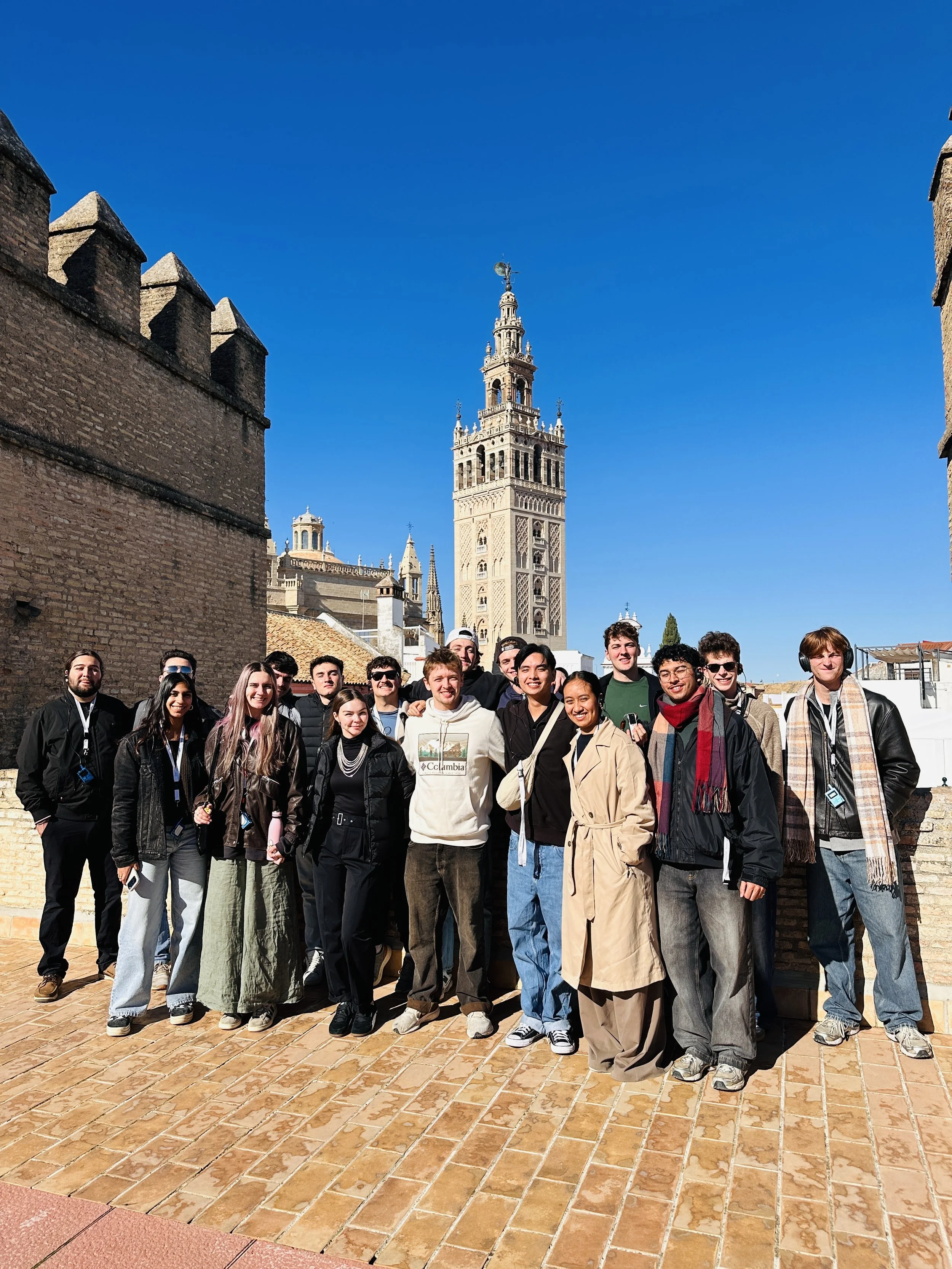 Group of people standing and waiting in line inside a historic building with ornate columns and decorative details.
