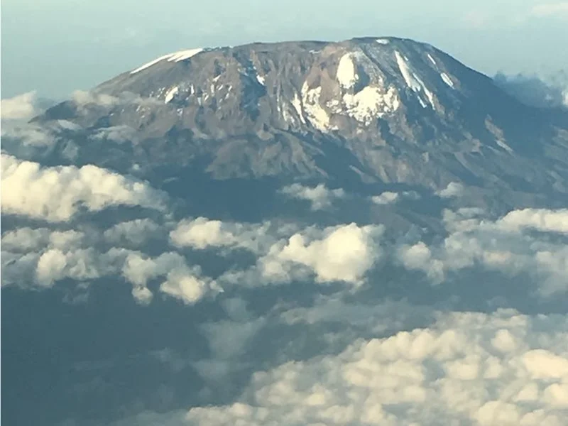 A snow-capped mountain peak above a layer of clouds.