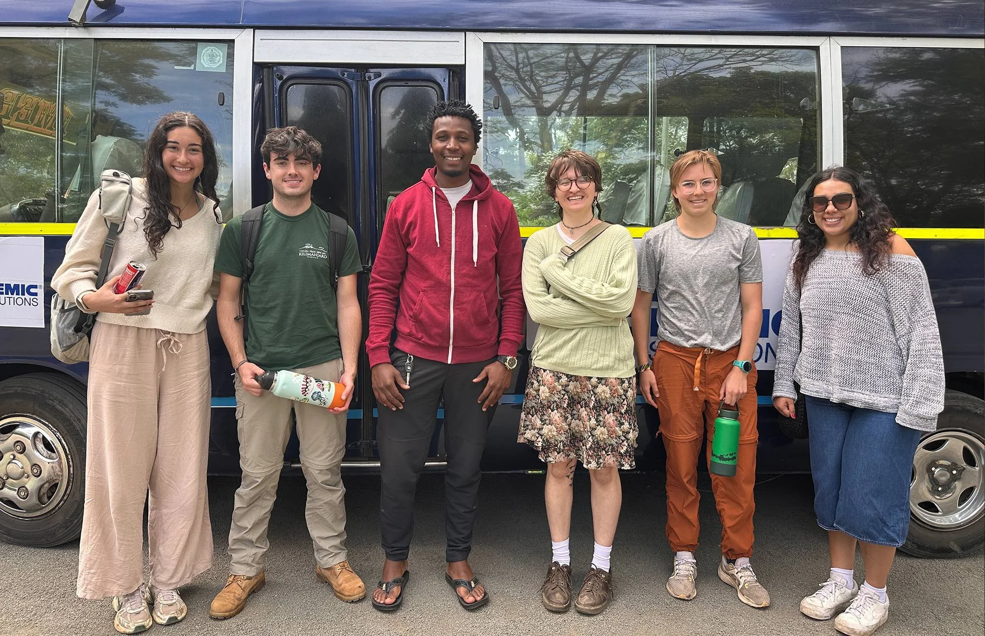 Group of diverse students standing together outdoors near a van.