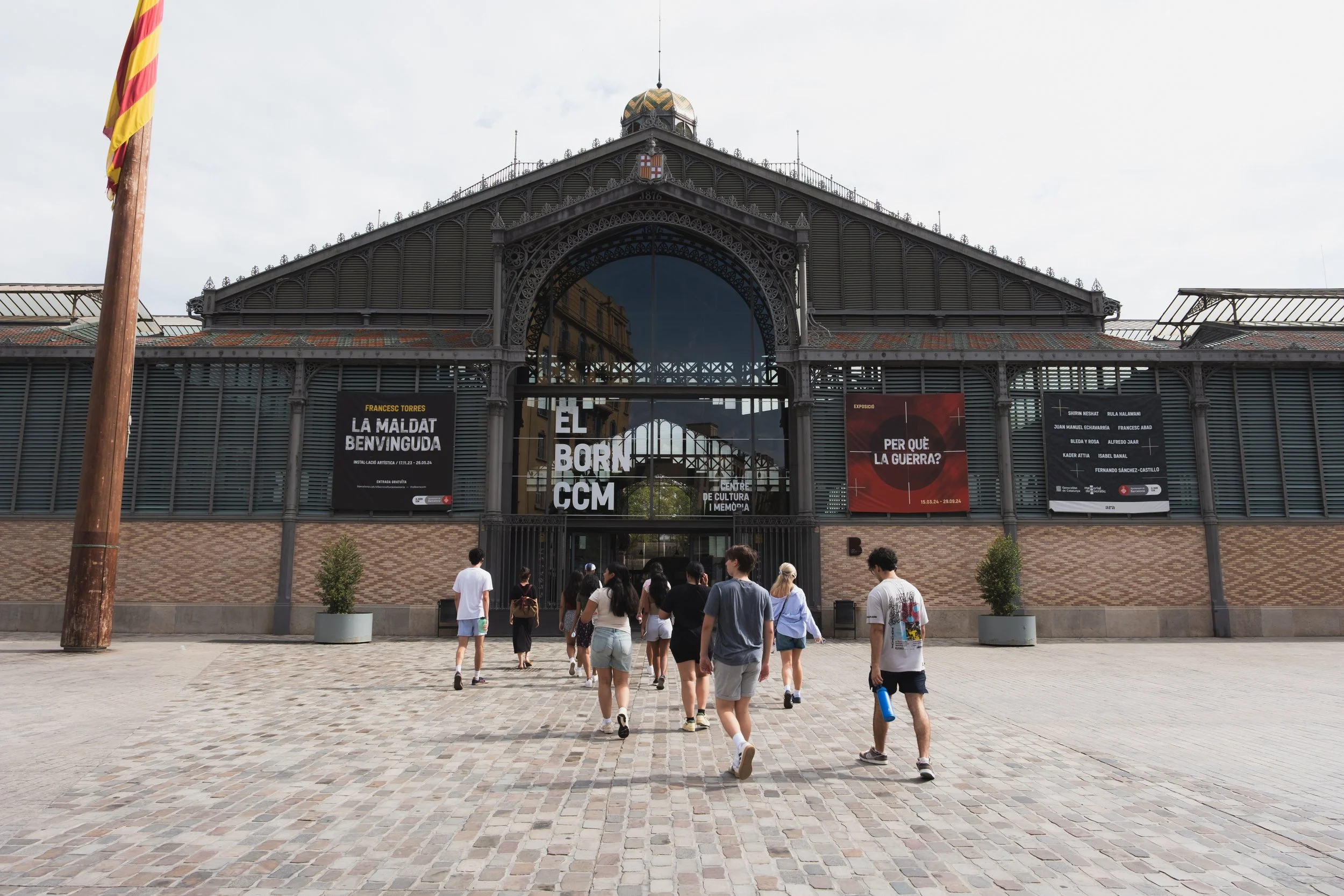 Cityscape of Barcelona with Sagrada Familia and surrounding urban area at sunset with mountains in the background.